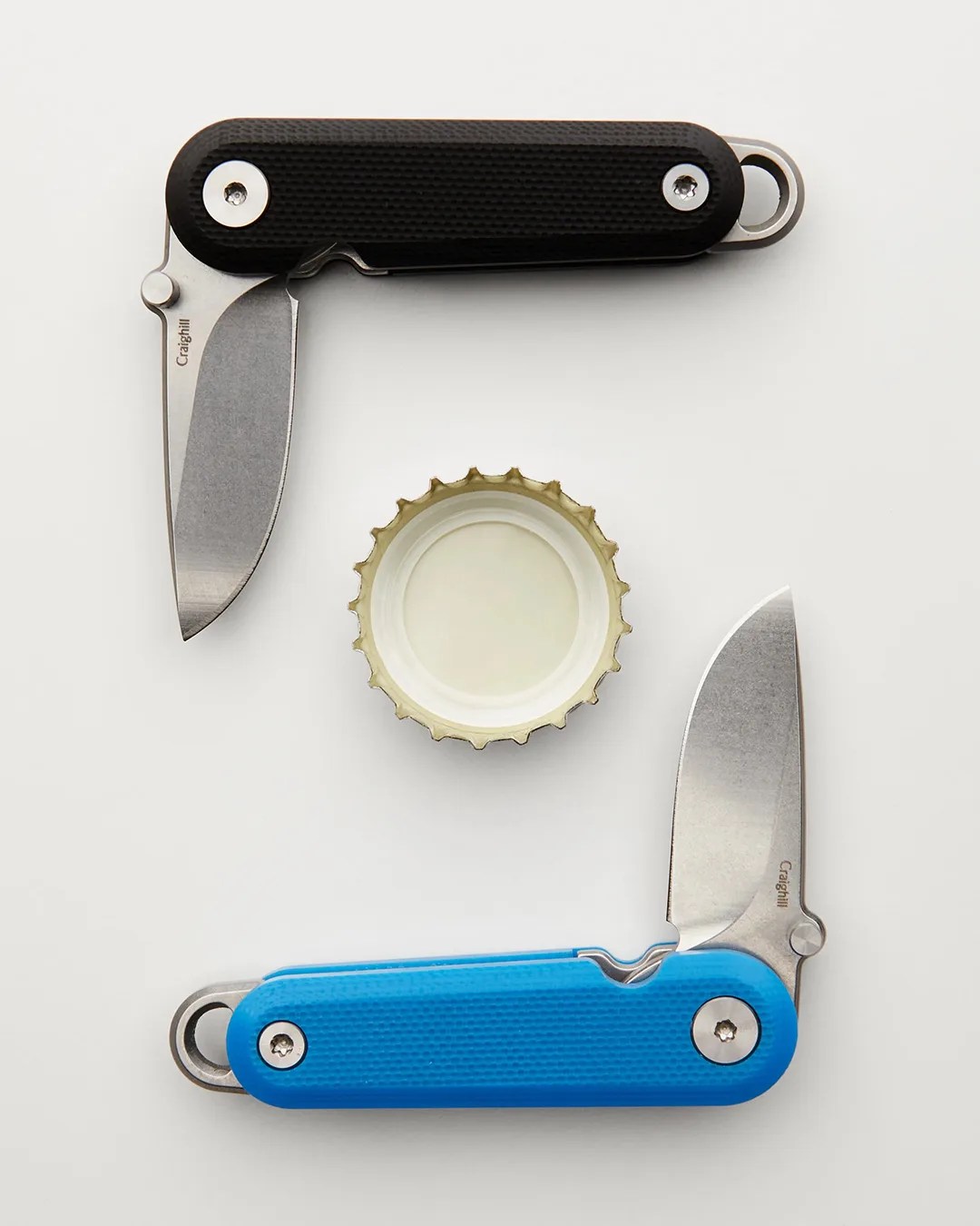Two Craighill G10 Lark Knives around bottlecap