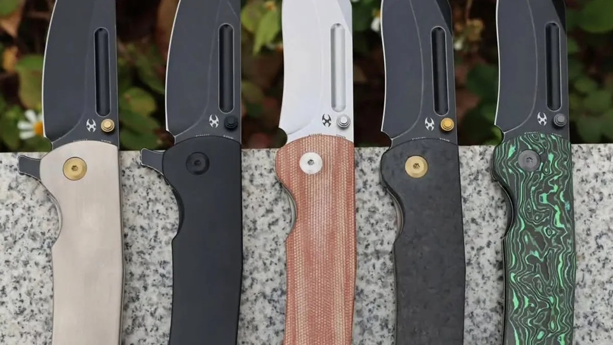 Closeup of Kansept Superhawk knives on slate in front of flowers