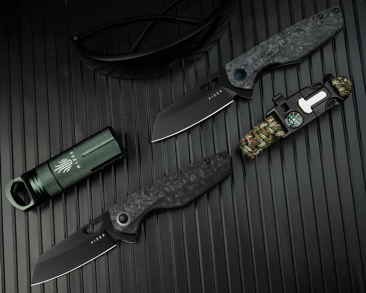 Kizer Sparrow knives next to stash container, sunglasses and paracord bracelet on corrugated black metal background