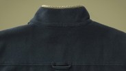 The top upper back shoulder area of the Outerknown Blanket Snap Popover in blank shown against a textured green background