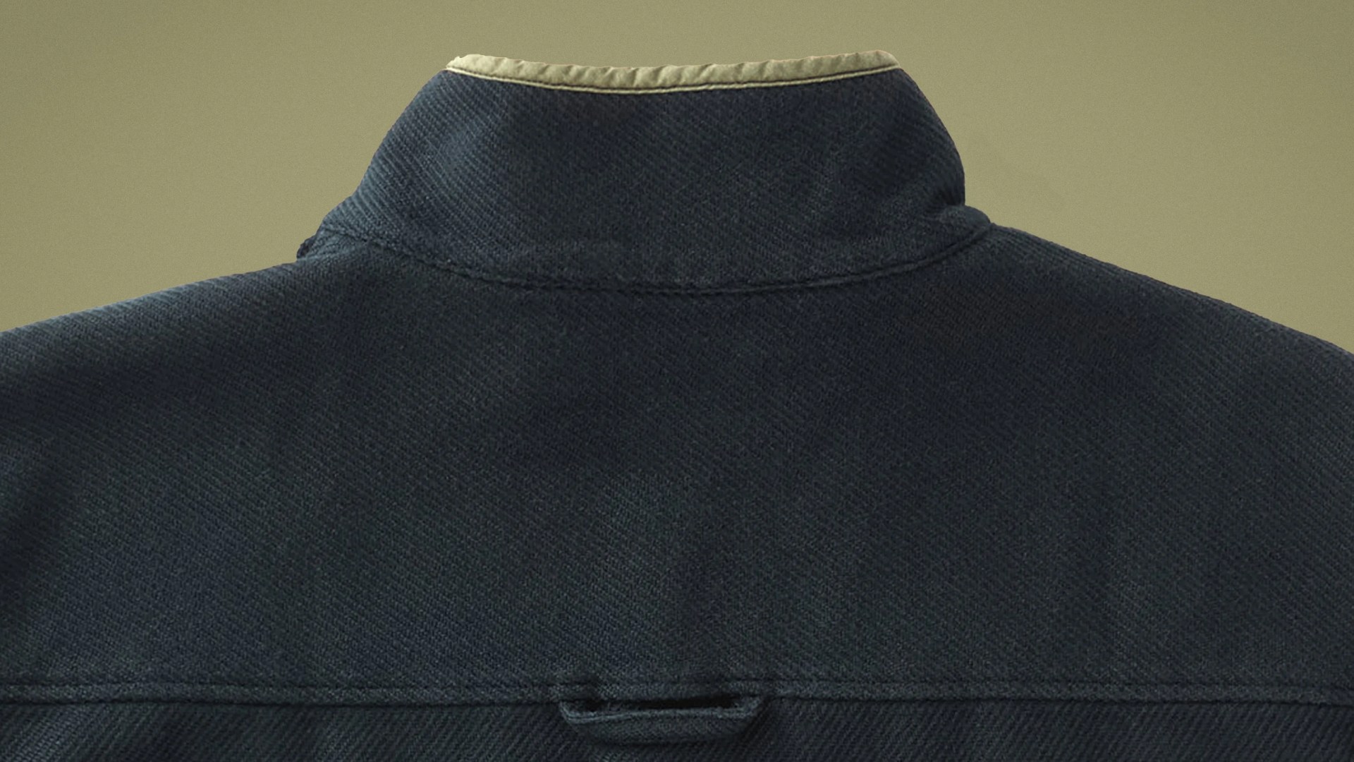 The top upper back shoulder area of the Outerknown Blanket Snap Popover in blank shown against a textured green background