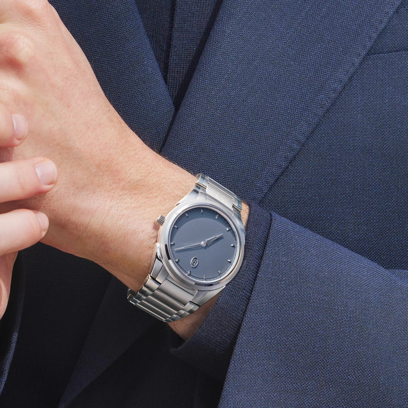 The Parmigiani PF Micro-Rotor Platinum Stone Blue is worn on the wrist of a male wearing a navy blazer. 