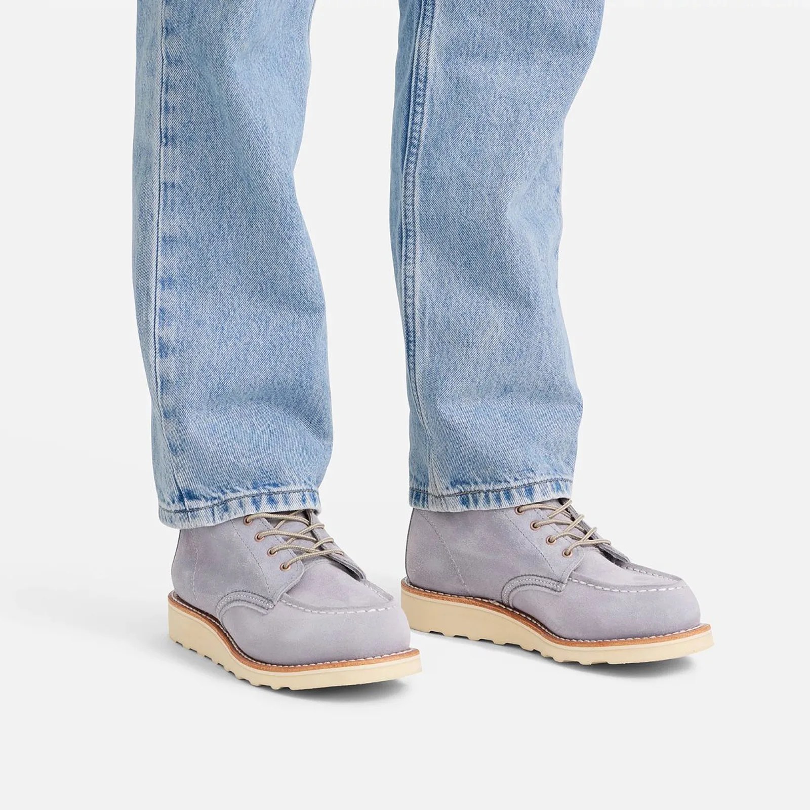 A pair of Red Wing Heritage Classic Moc boots in a new Lavender color, which looks like light purple, being worn by a female model wearing blue jeans. The pants and jeans are shown from right below the knee down. 