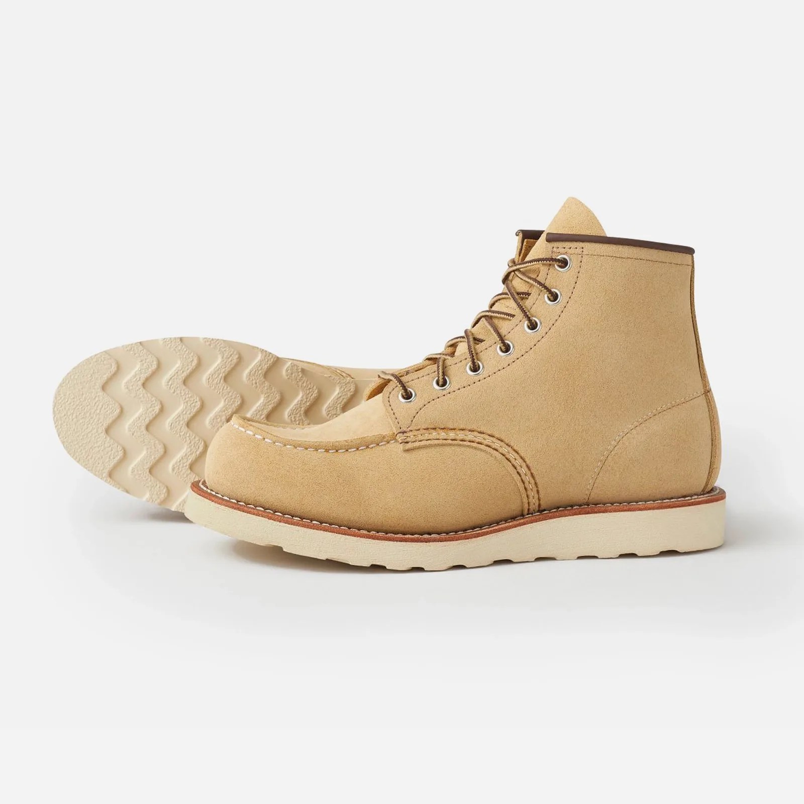 A pair of Red Wing Heritage Classic Moc boots in a light tannish yellow colored called Hawthorne. One boot is standing up in profile with the toe facing to the left of the image frame. The other boot is shown on its side, revealing the sole. 