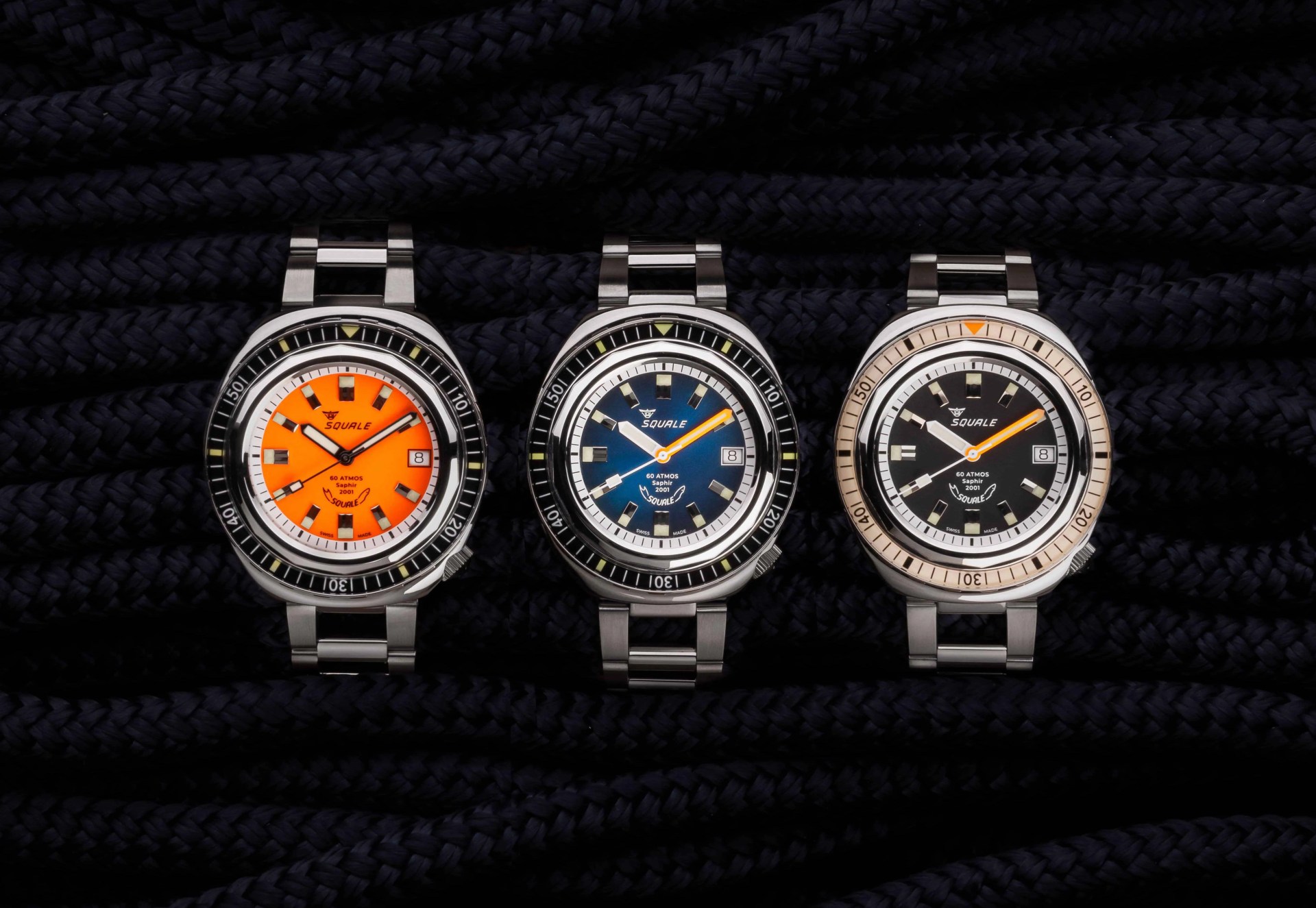 Three Squale 2001 dive watches shown face on top of a clump of black nautical rope.