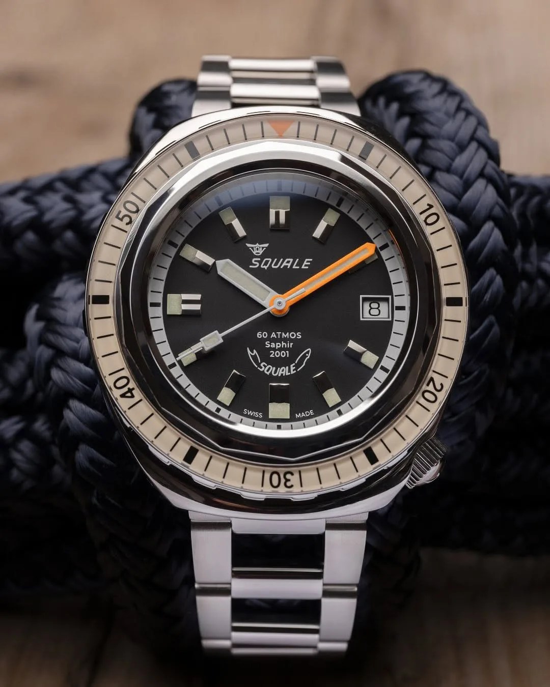The Squale 2001 dive watch shown face on top of a clump of black nautical rope. 