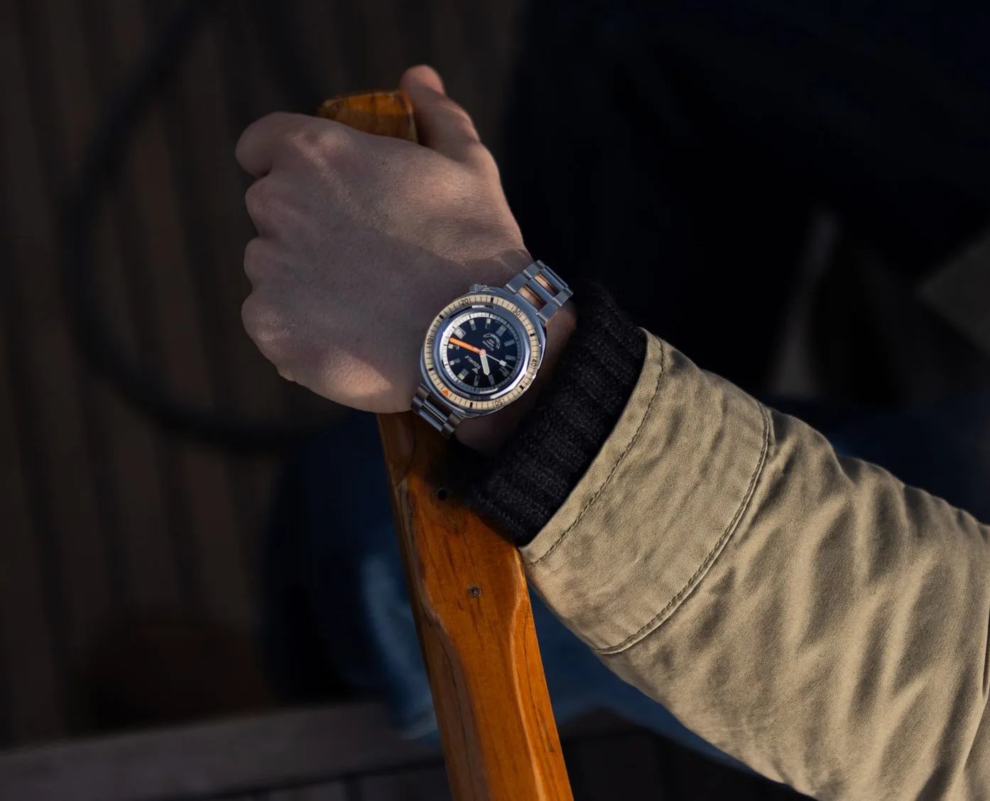 The Squale 2001 shown worn on a male wrist holding the end of a boating oar / handle. The wearer is shown wearing a dark brown sweater and light tan jacket. 