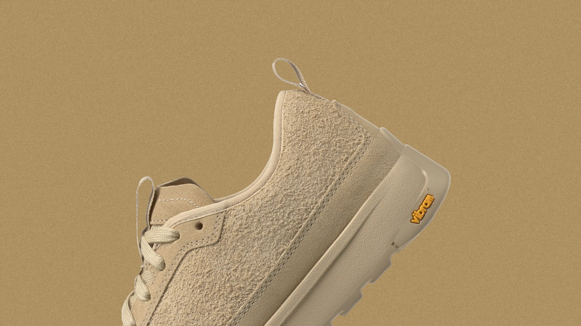 A view of the heel of The North Face Clyffe Suede Shoes shown at an angle against a speckled tan background