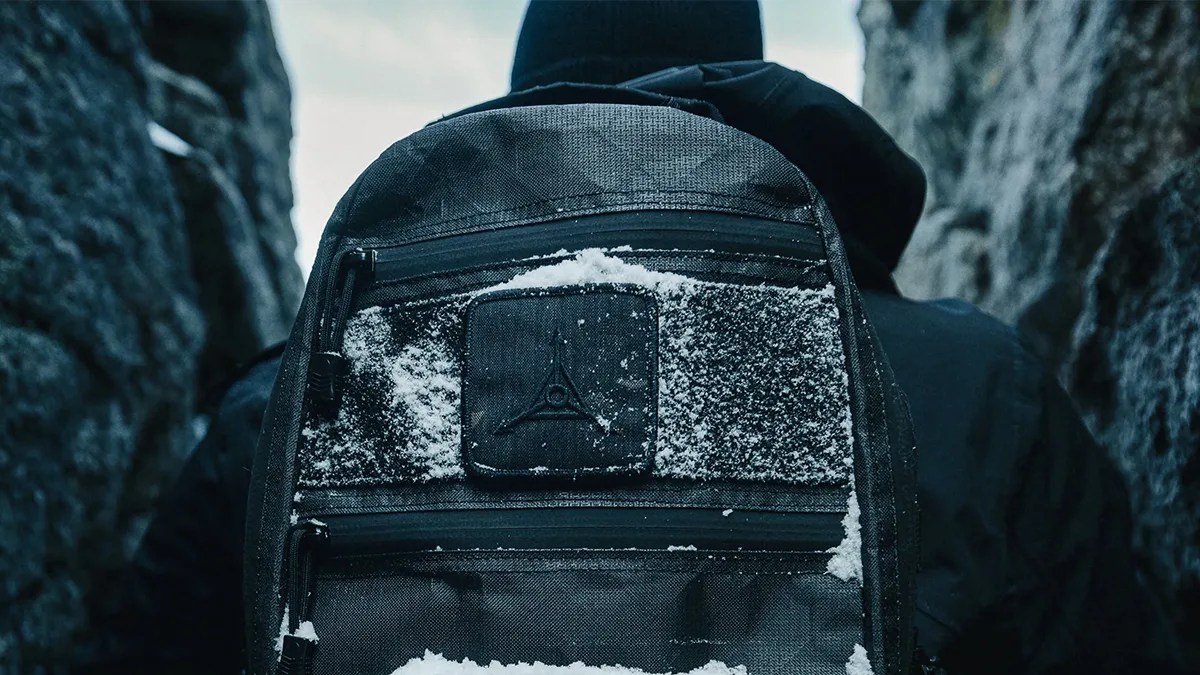 closeup of snow-covered Triple Aught Design Black Magic Edition FAST Pack Litespeed backpack on man's back in canyon