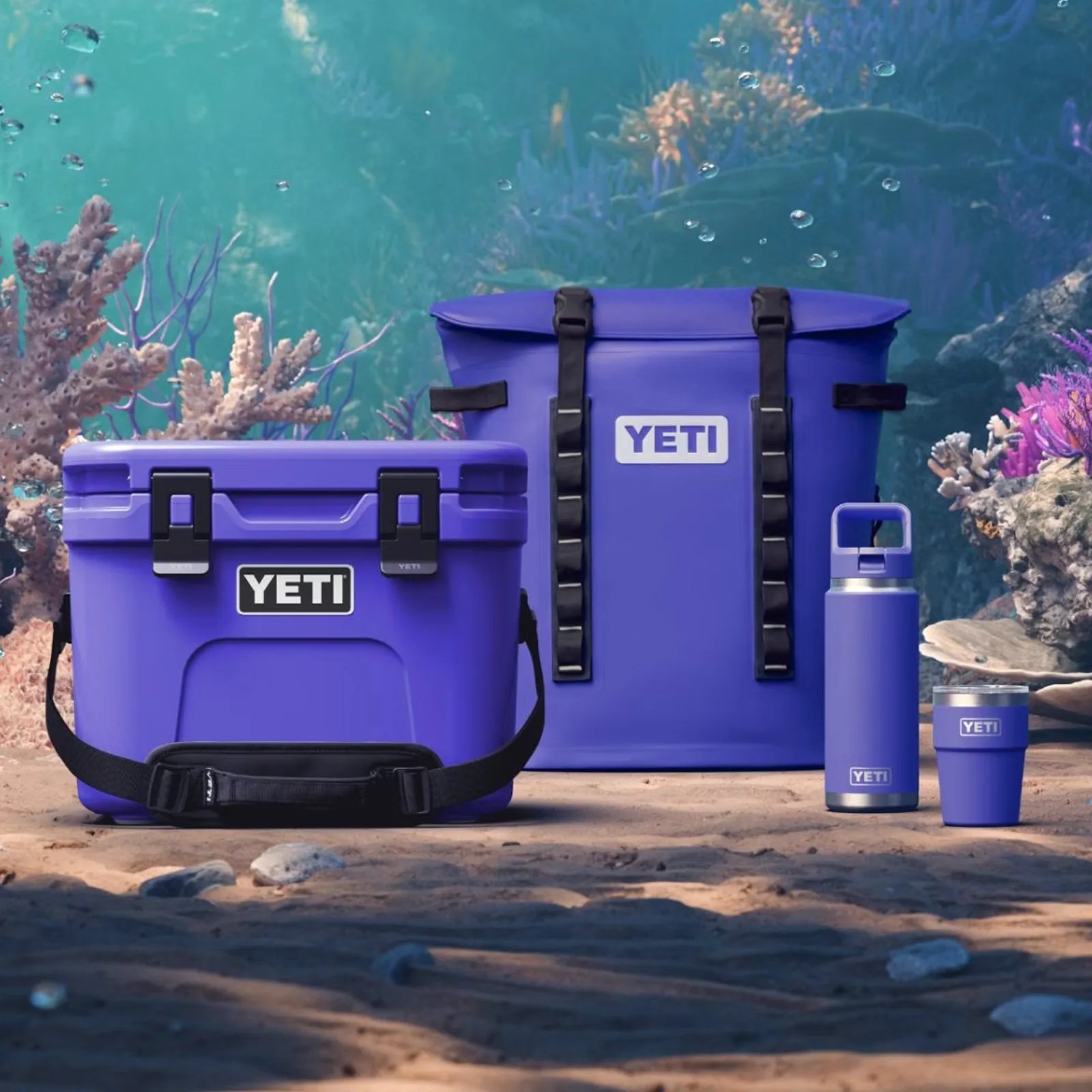 A series of Yeti products in Ultramarine Violet shown illustrated sitting on the bottom of the ocean floor surrounded by coral