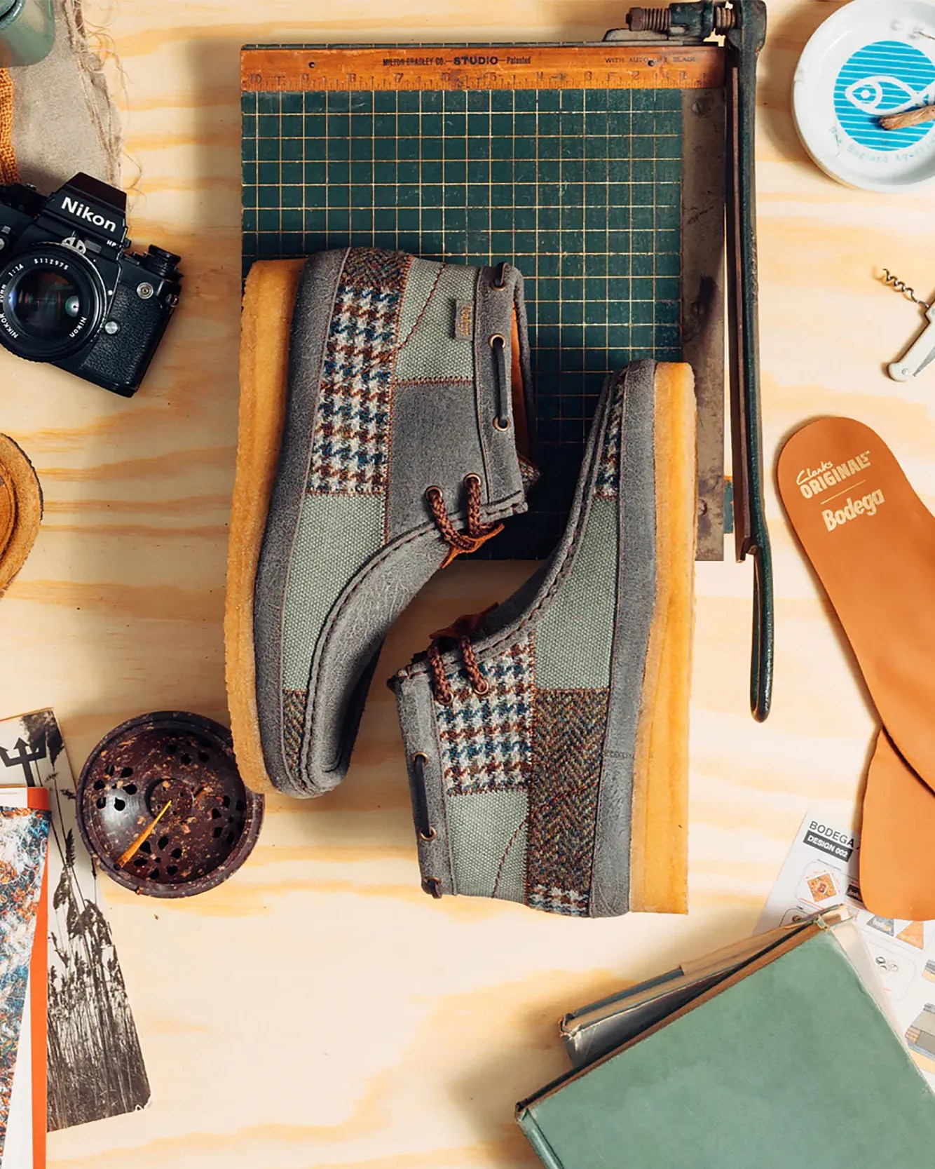 a pair of patchwork Clarks Wallabee boots laying on a desk