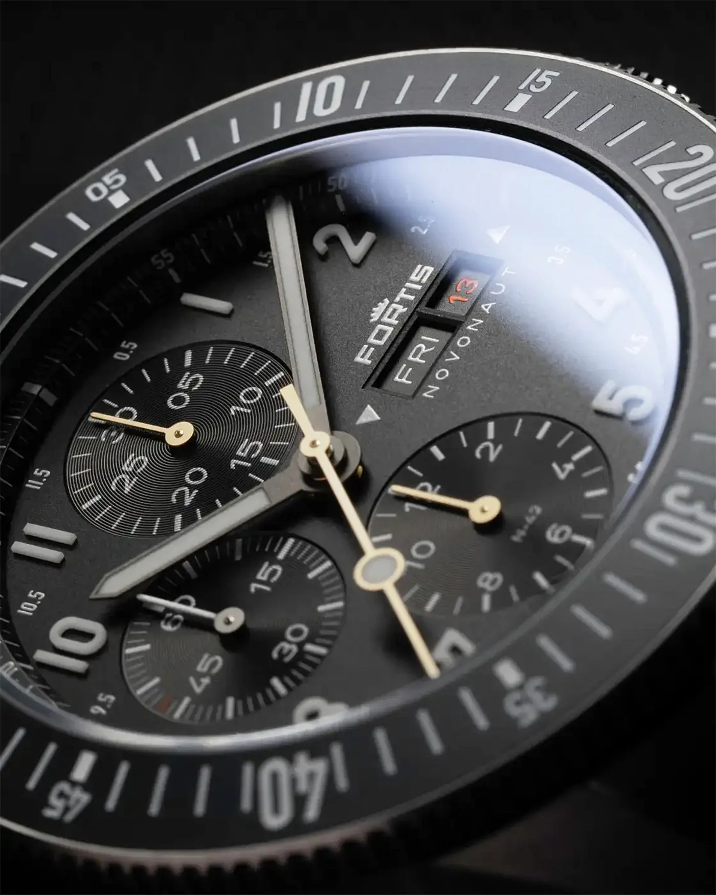 a black chronograph dial with gold chronograph register hands