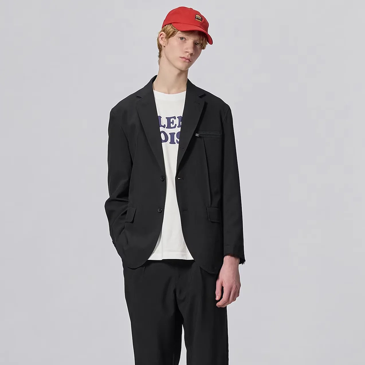 a man in a black suit, t-shirt and red hat
