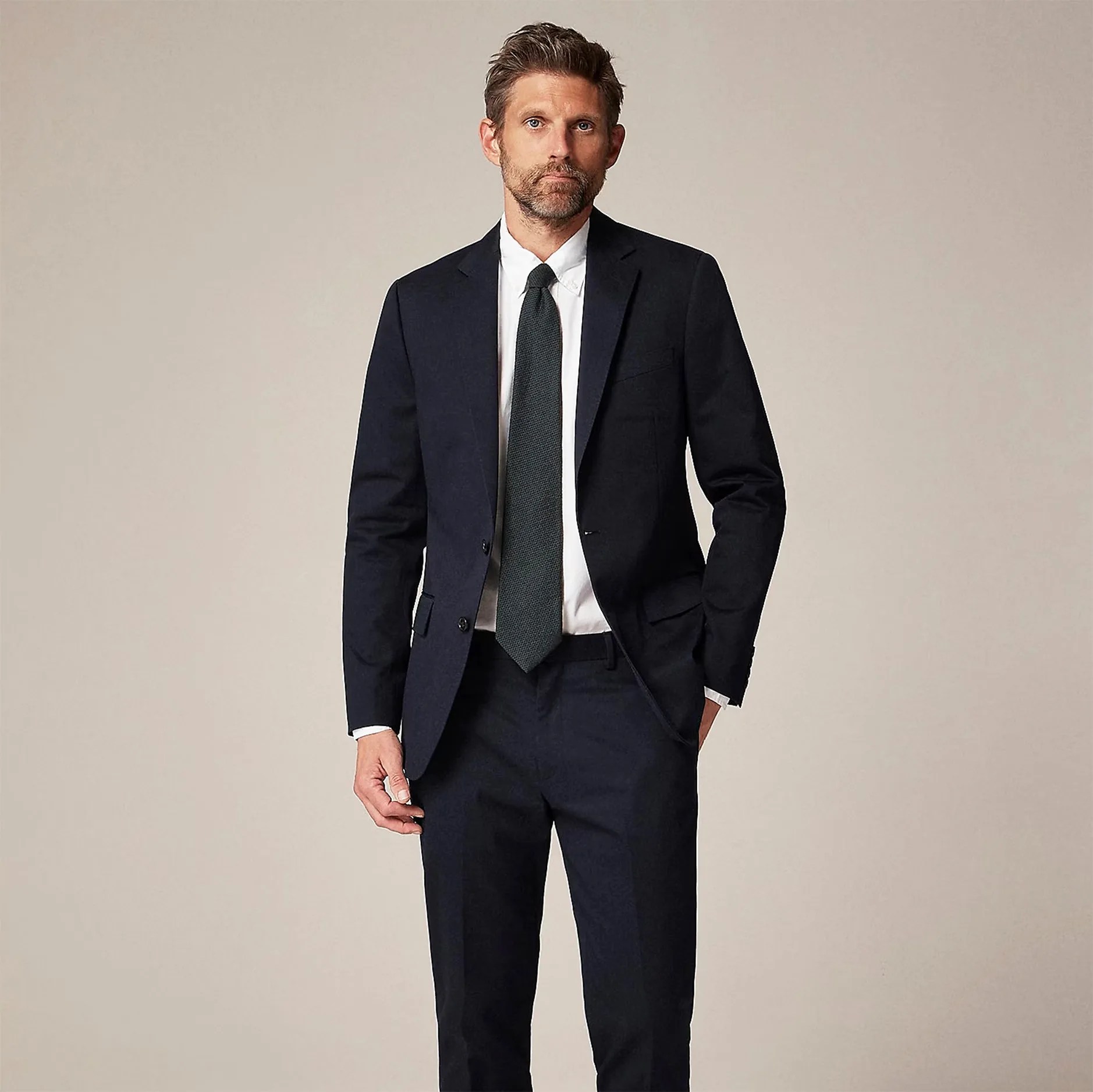 a man in a navy blue chino suit with a green tie