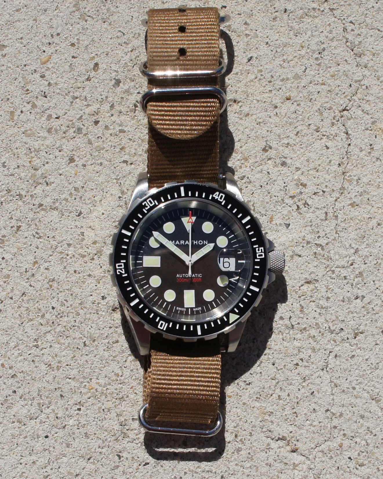 a black marathon dive watch on a khaki nylon strap
