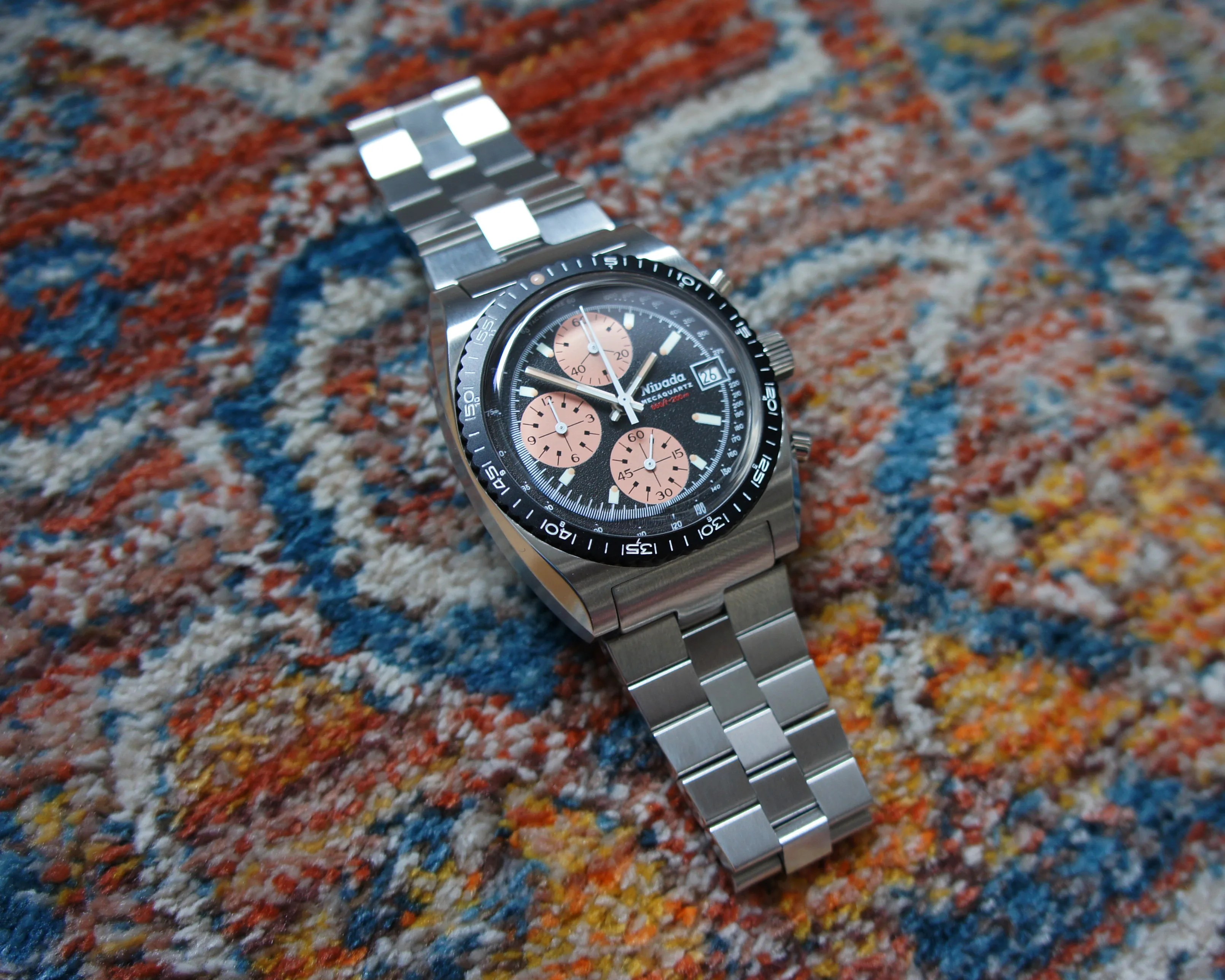 a Nivada Grenchen chronograph watch laying on a rug
