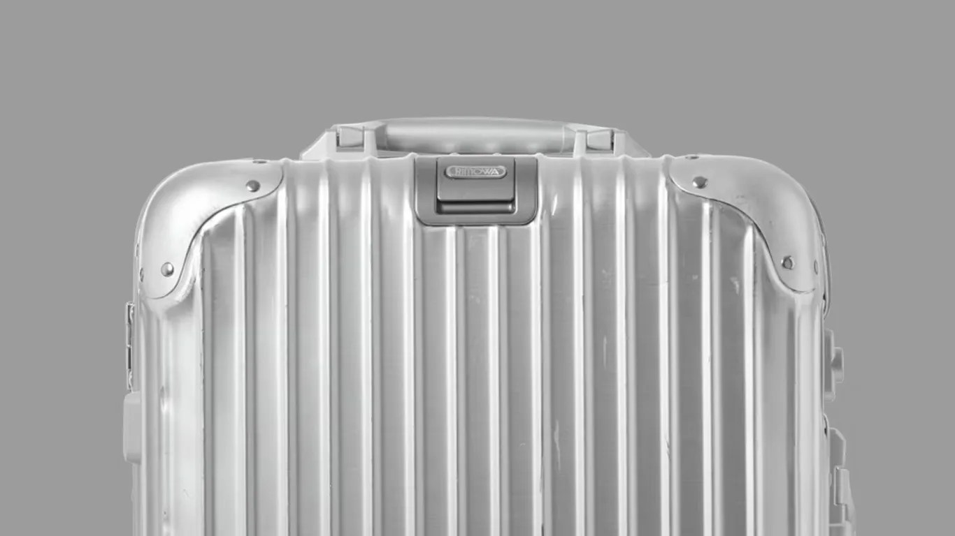 a beat up rimowa aluminum suitcase