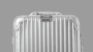 a beat up rimowa aluminum suitcase