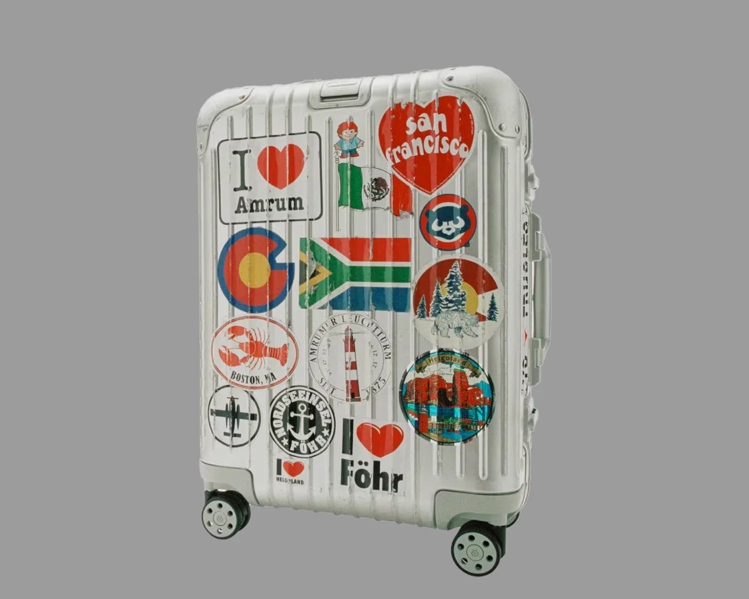 a vintage rimowa aluminum suitcase covered in travel stickers
