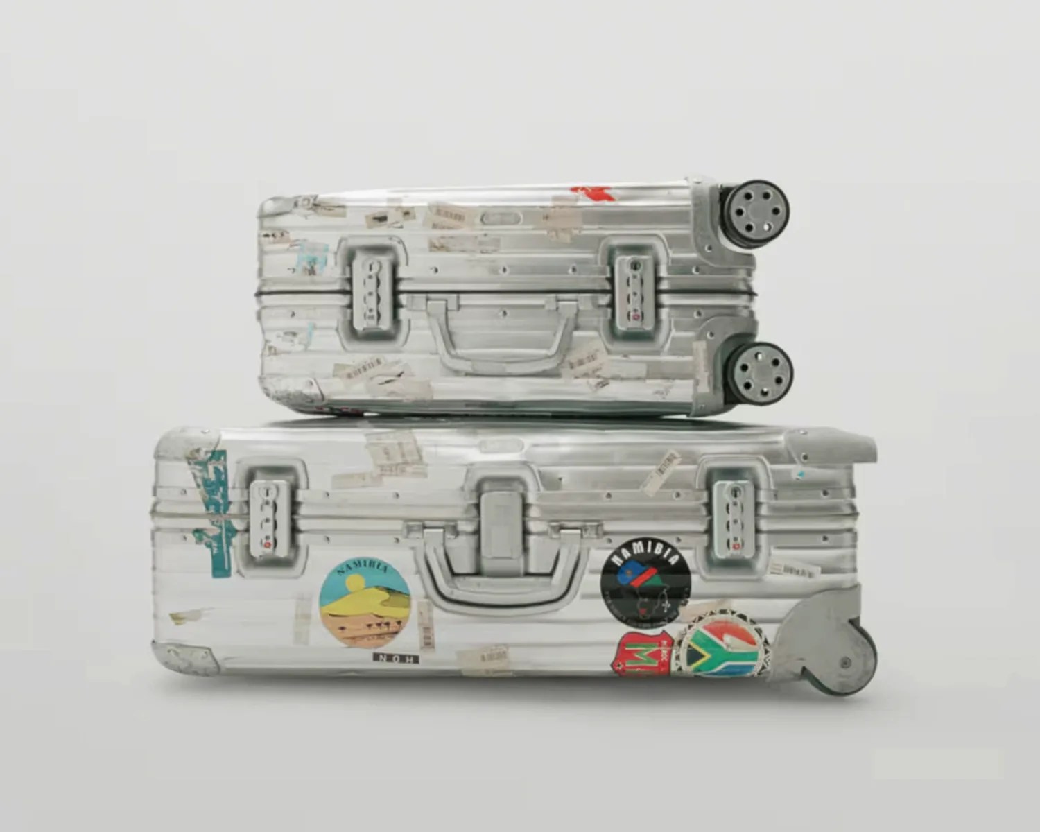 two beat up rimowa aluminum suitcases