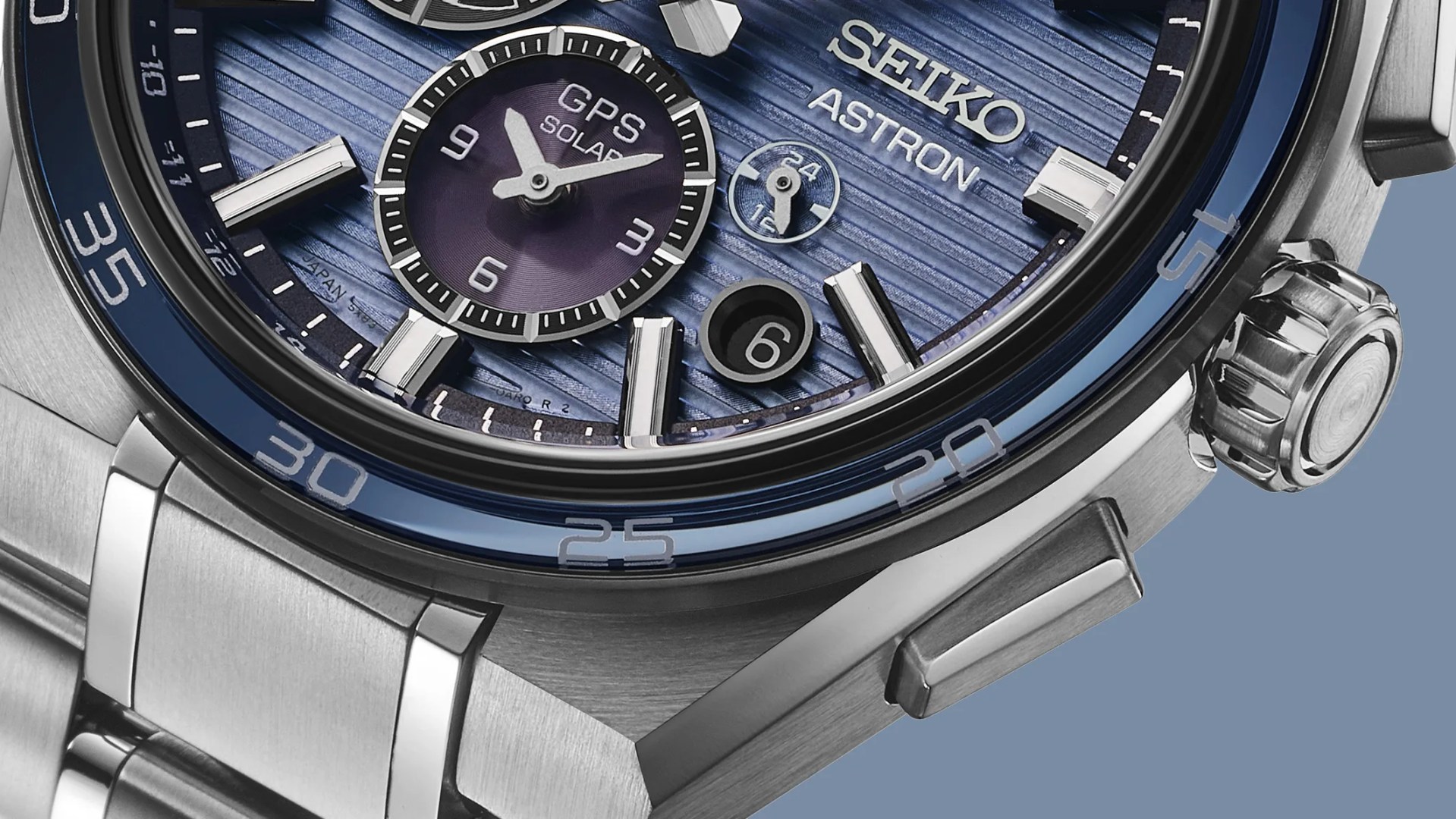 a close up of the dial, bezel and crown of a steel Seiko Astron chronograph