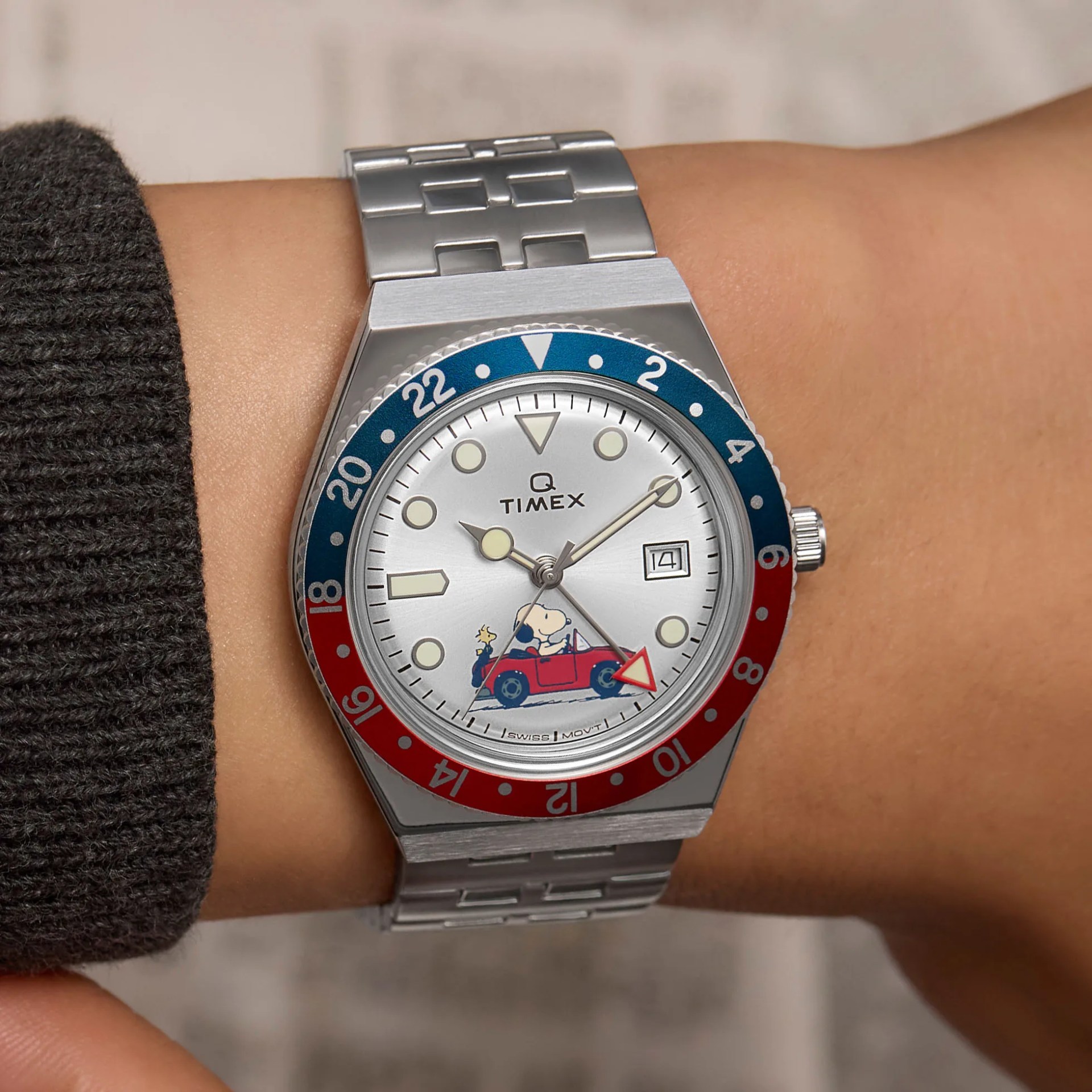 a steel gmt watch with Snoopy driving a car on the dial