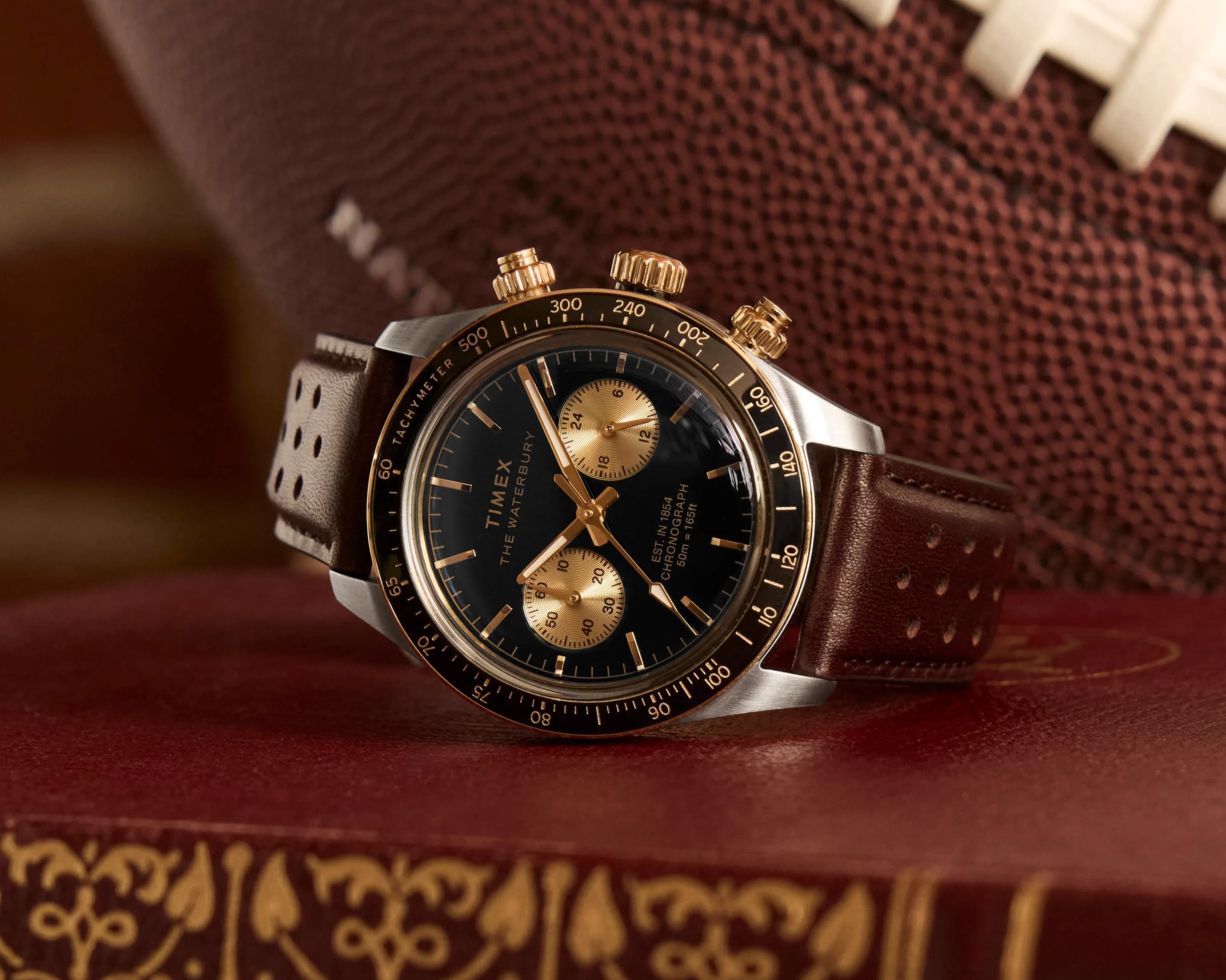a black and gilt Timex chronograph watch laying on top of a book