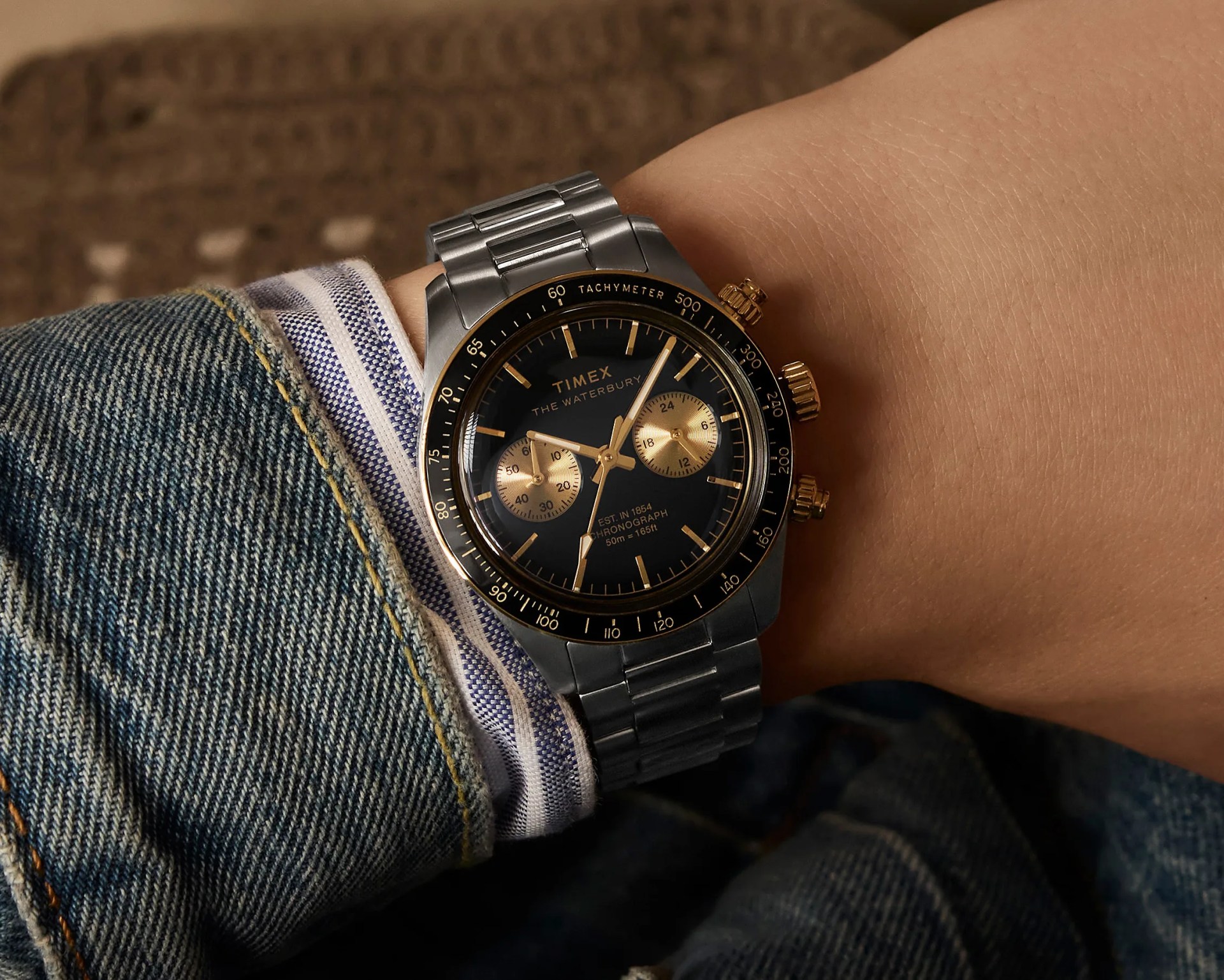 a black and gilt Timex chronograph on a man's wrist