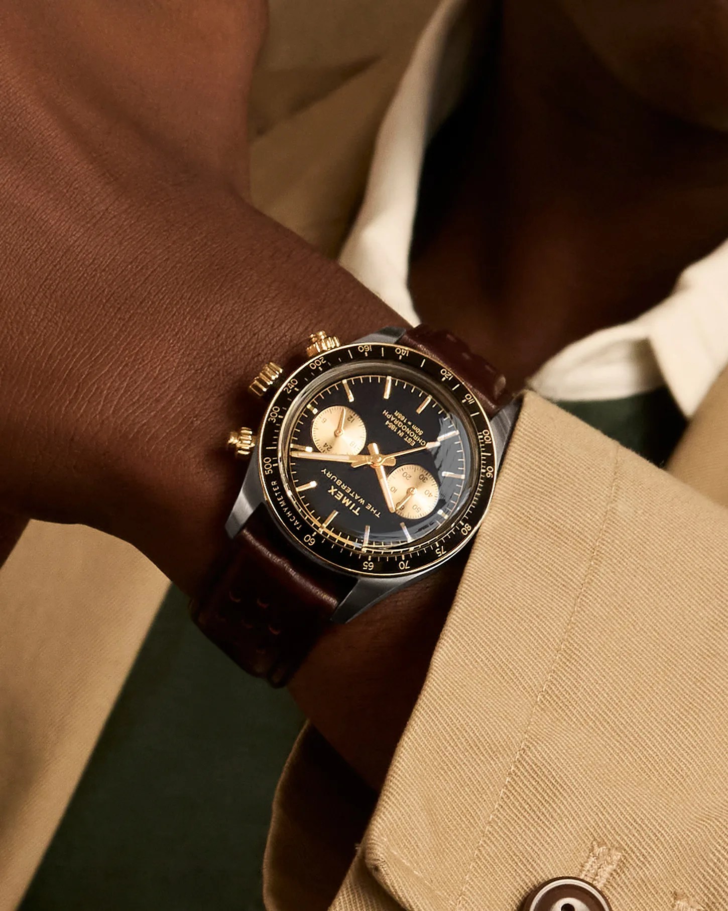 a black and gilt Timex chronograph watch on a man's wrist