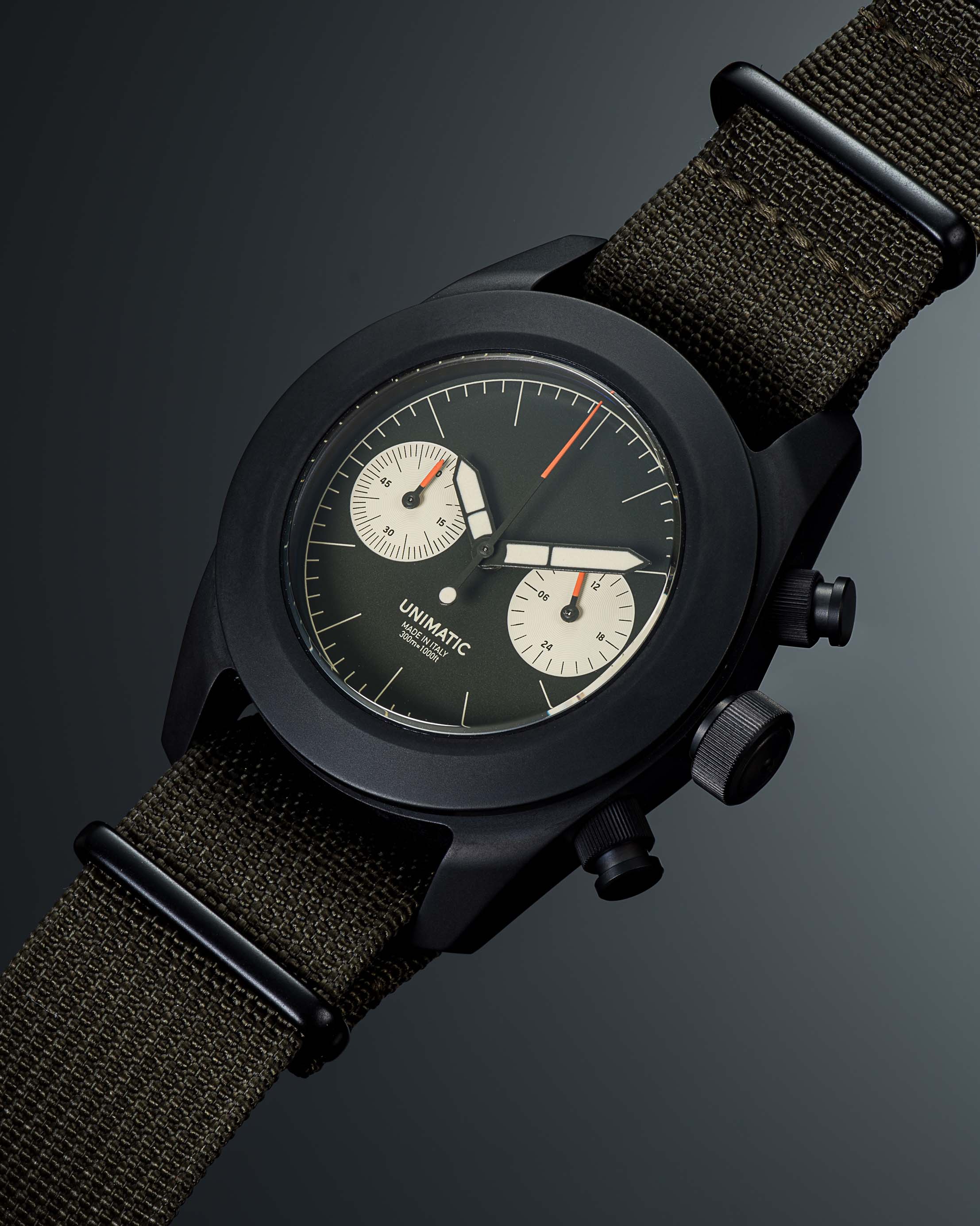 a black chronograph watch with an olive strap