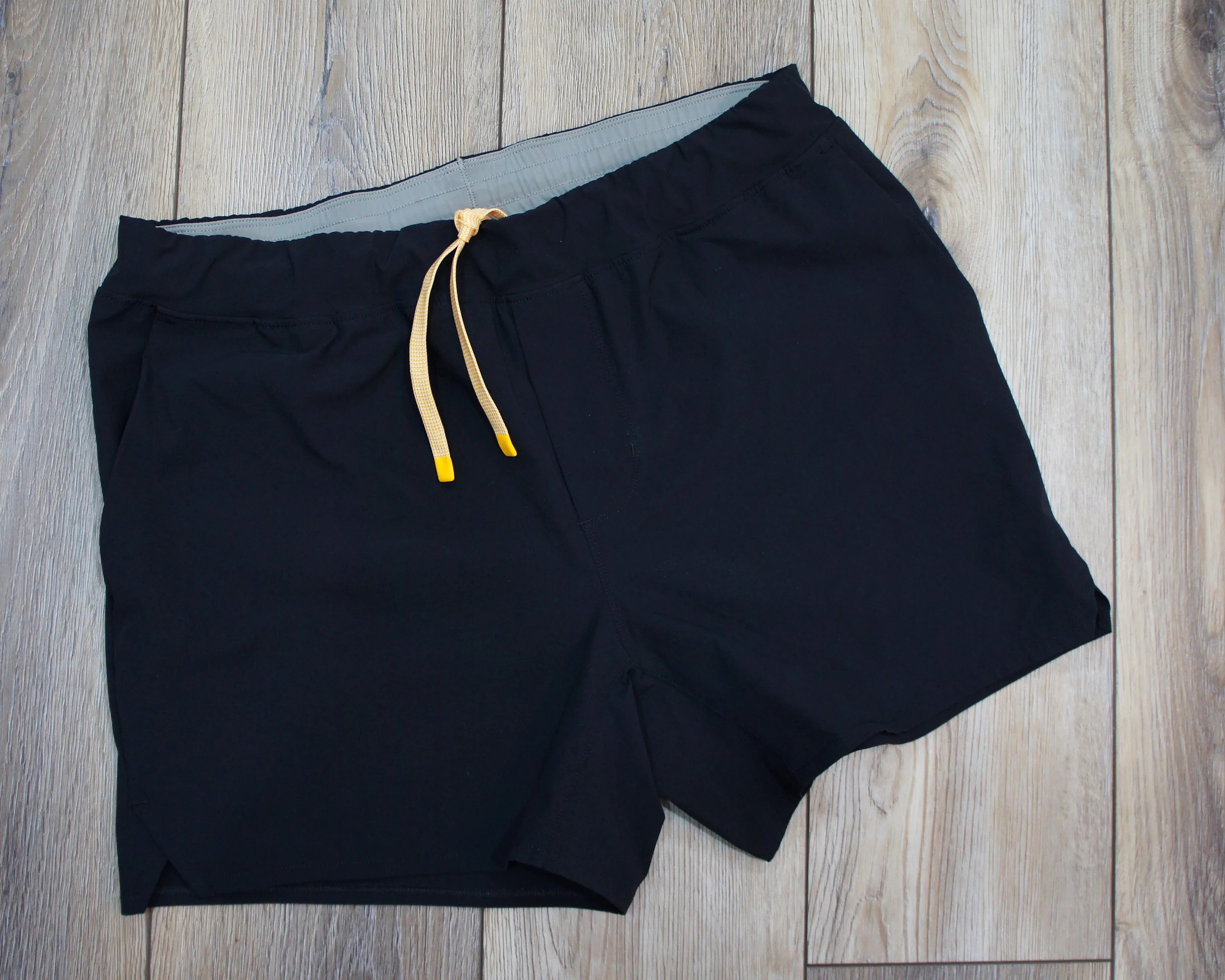 a pair of black Wellen running shorts with a yellow drawstring