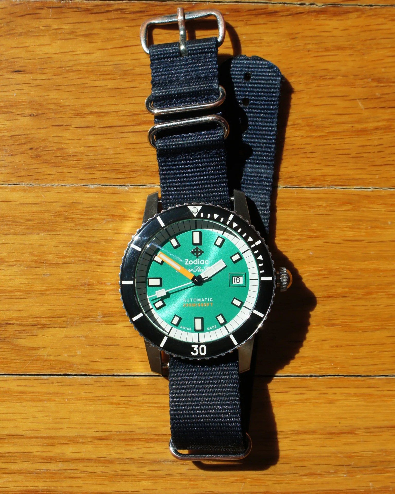 a green Zodiac dive watch on a blue nylon strap