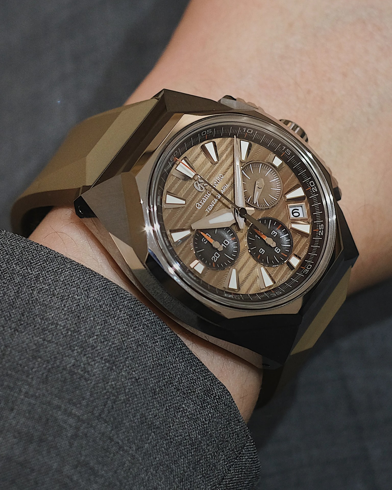 The Grand Seiko Tokyo Lion watch worn on a male wrist shown slightly above the cuff of a dark grey suit jacket sleeve.