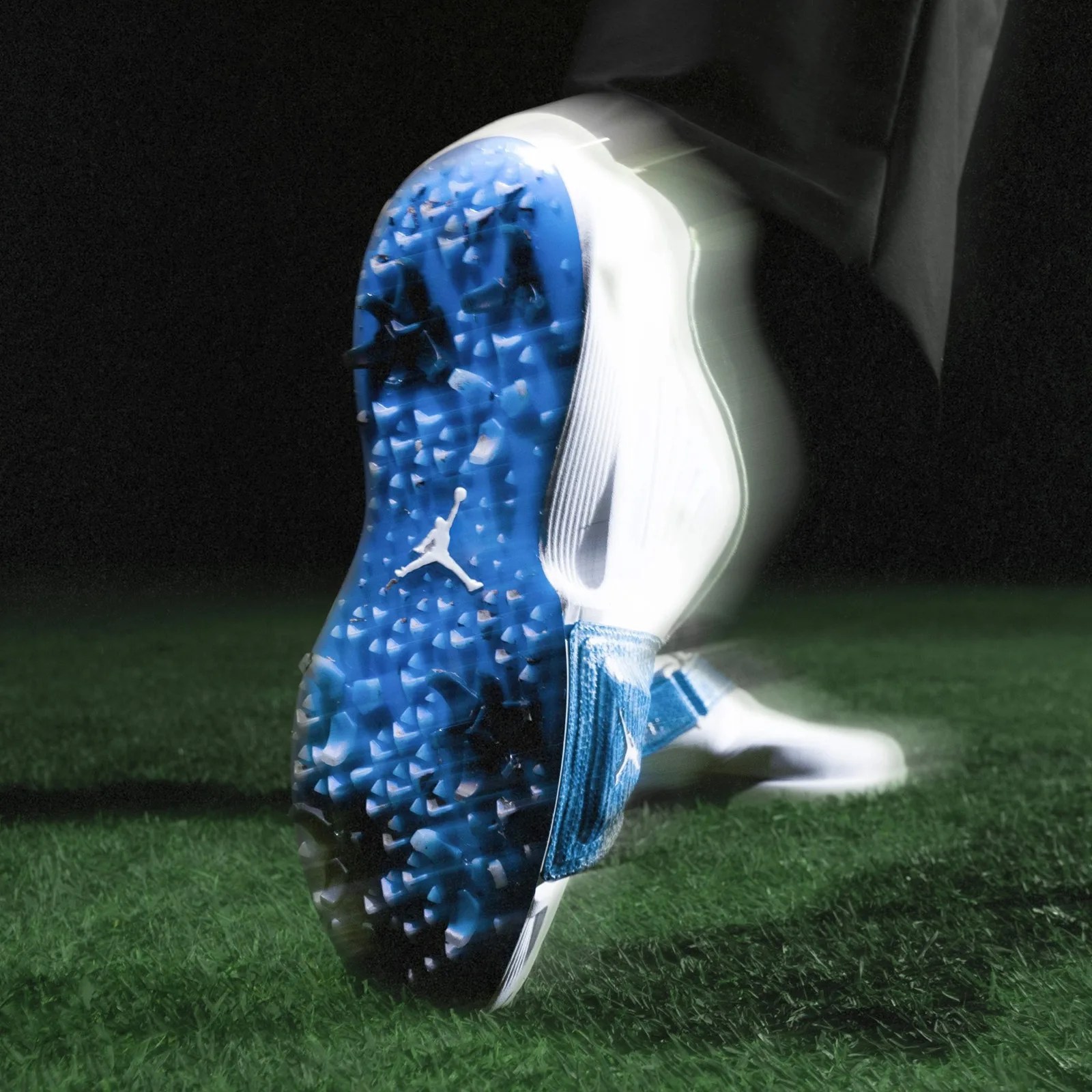 A Jordan Air Rev Golf shoe shown being worn on a golfer's foot in mid-swing with blurred edges. 