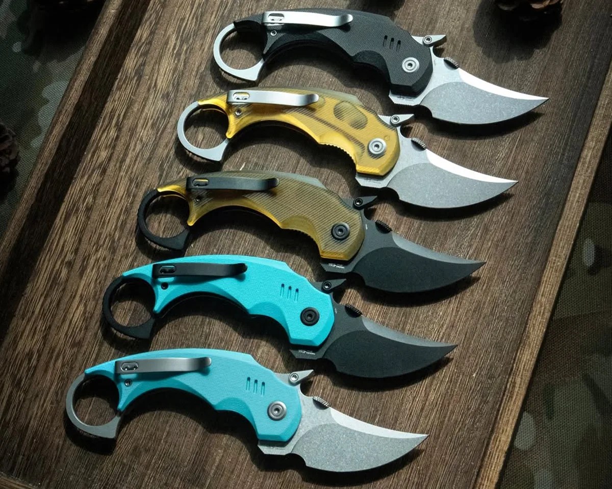 Kubey Jaw Folding Karambit knives on wooden valet tray