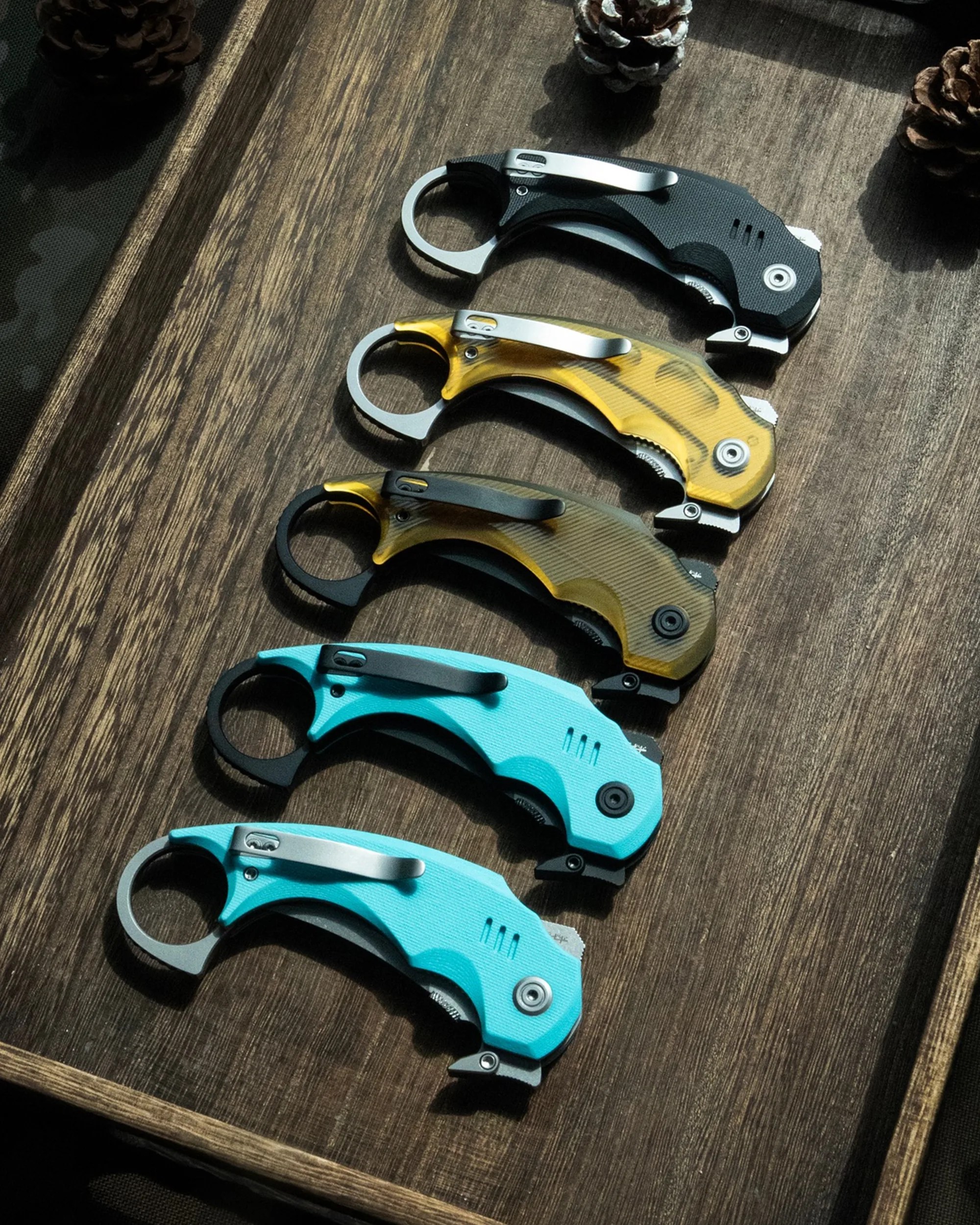 Kubey Jaw Folding Karambit knives closed on wooden valet tray