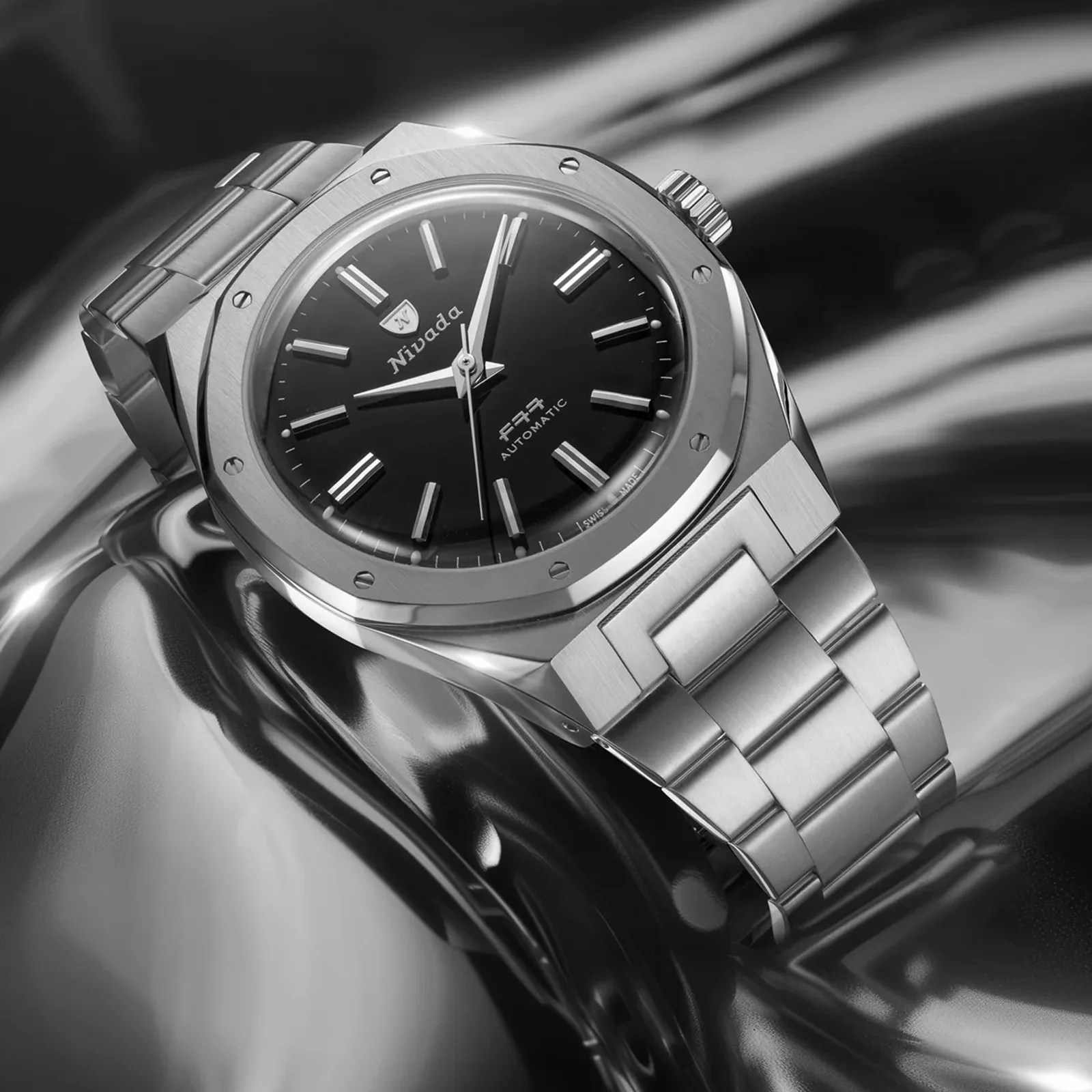 The Nivada Grenchen F77 MarkII SST in black shown against a liquid metal background. 