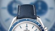 The top of the dial of the Omega Speedmaster Anniversary Series "Silver Snoopy Awards" worn by Rory McIlroy during his 2025 Master's Win shown against a blurred blue background.