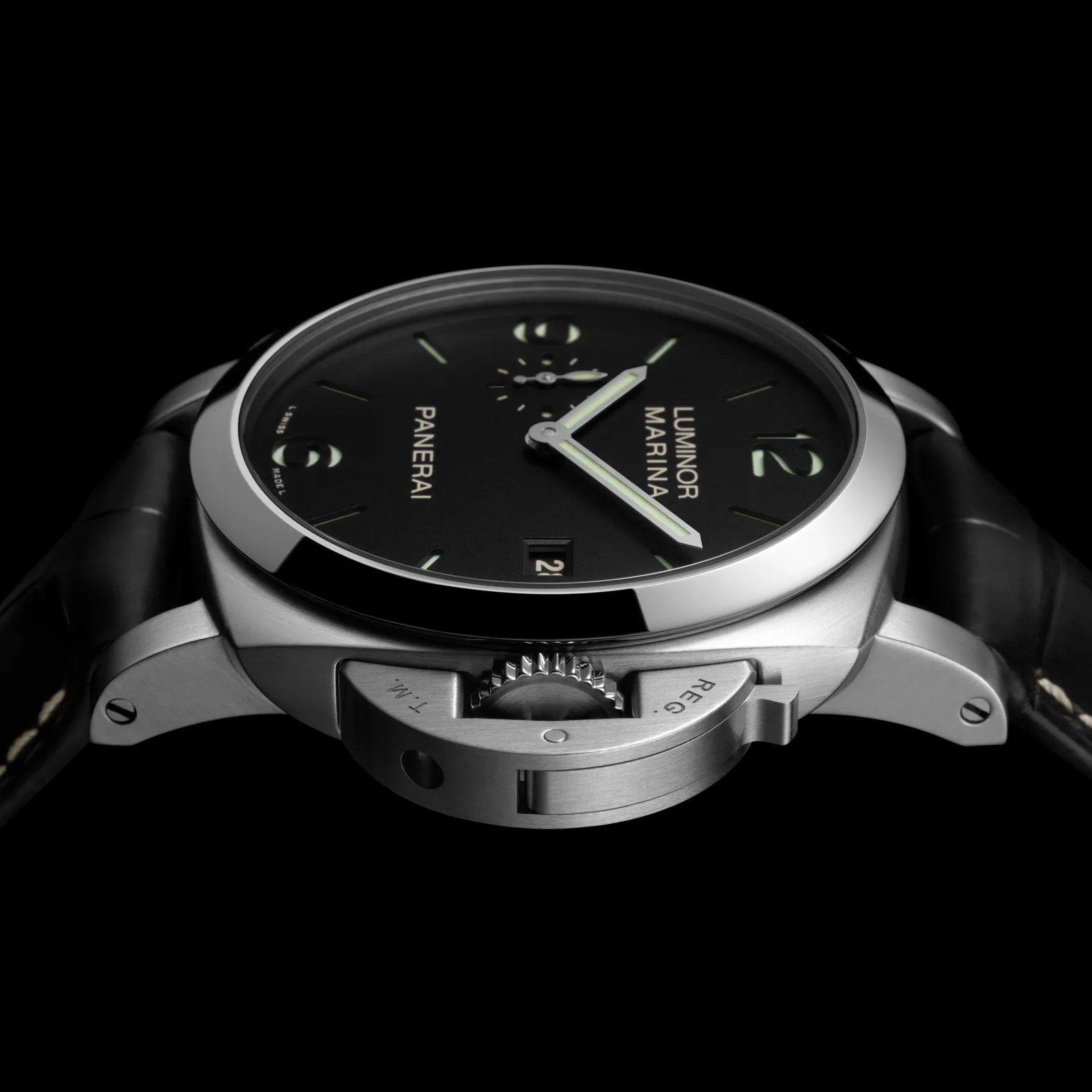 A 2025 Panerai Luminor Marina series watch with a black dial shown at an angle with the watch case laying flat against a black background. 