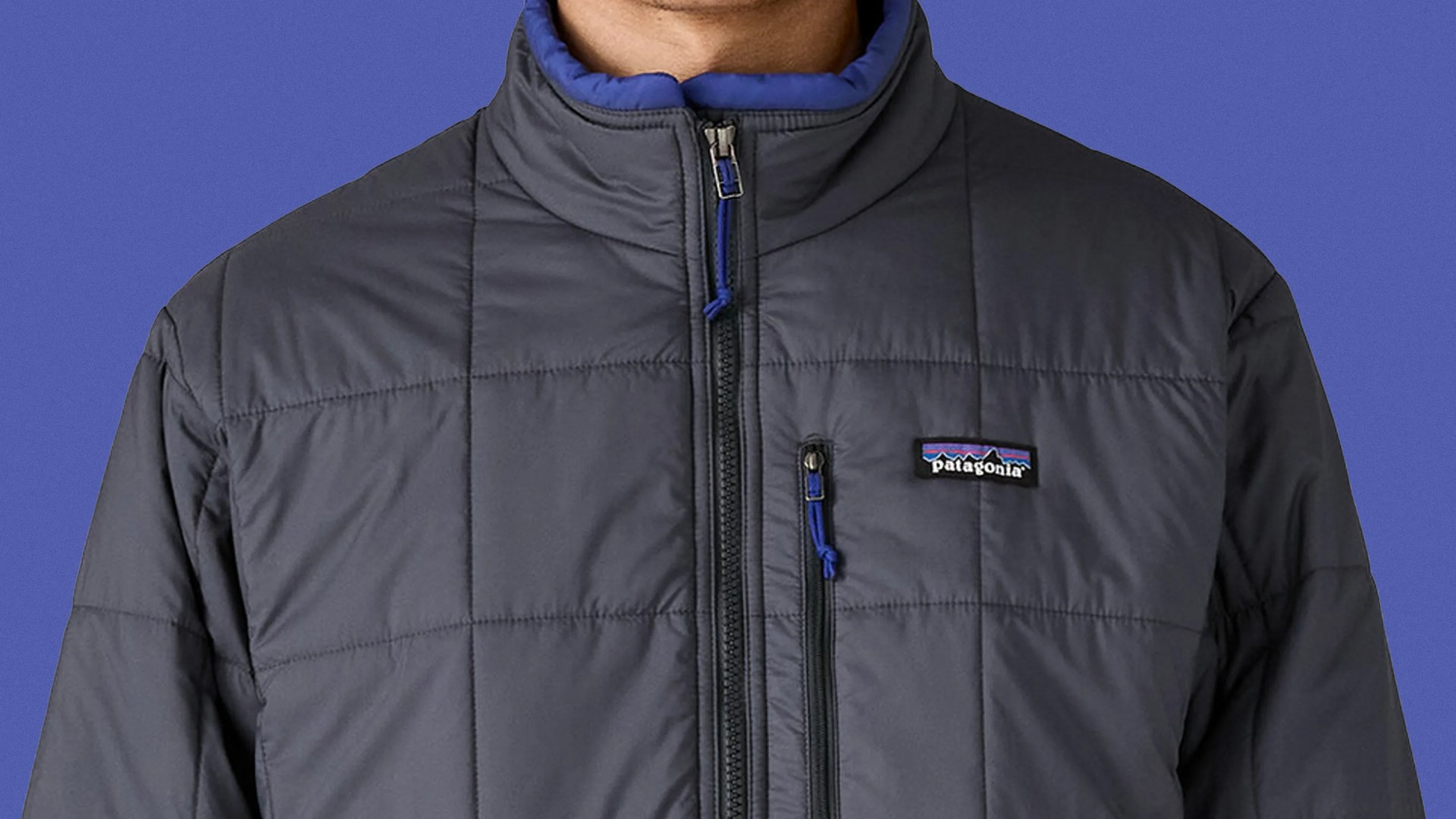 A male model shown from the neck down to mid torso wearing a Patagonia Light Gust Jacket in grey.