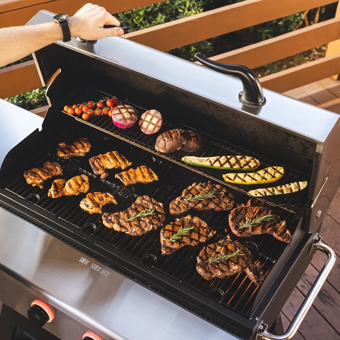 An image of a Recteq X-Fire Pro 825 pellet grill with the lid lifted to reveal a full cooking surface of meats and vegetables. 