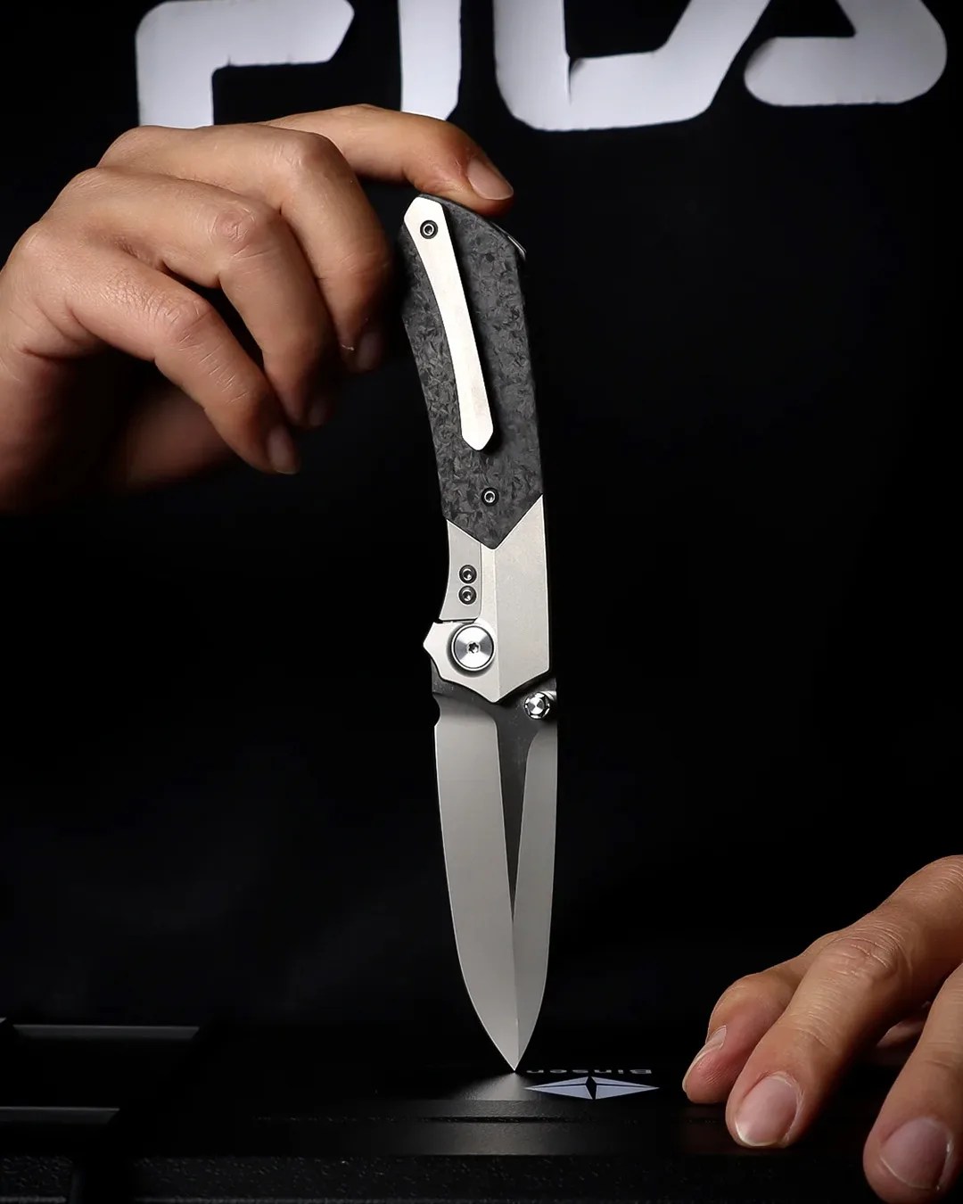 Person balancing Remette RT-Meteor knife on its tip with hands