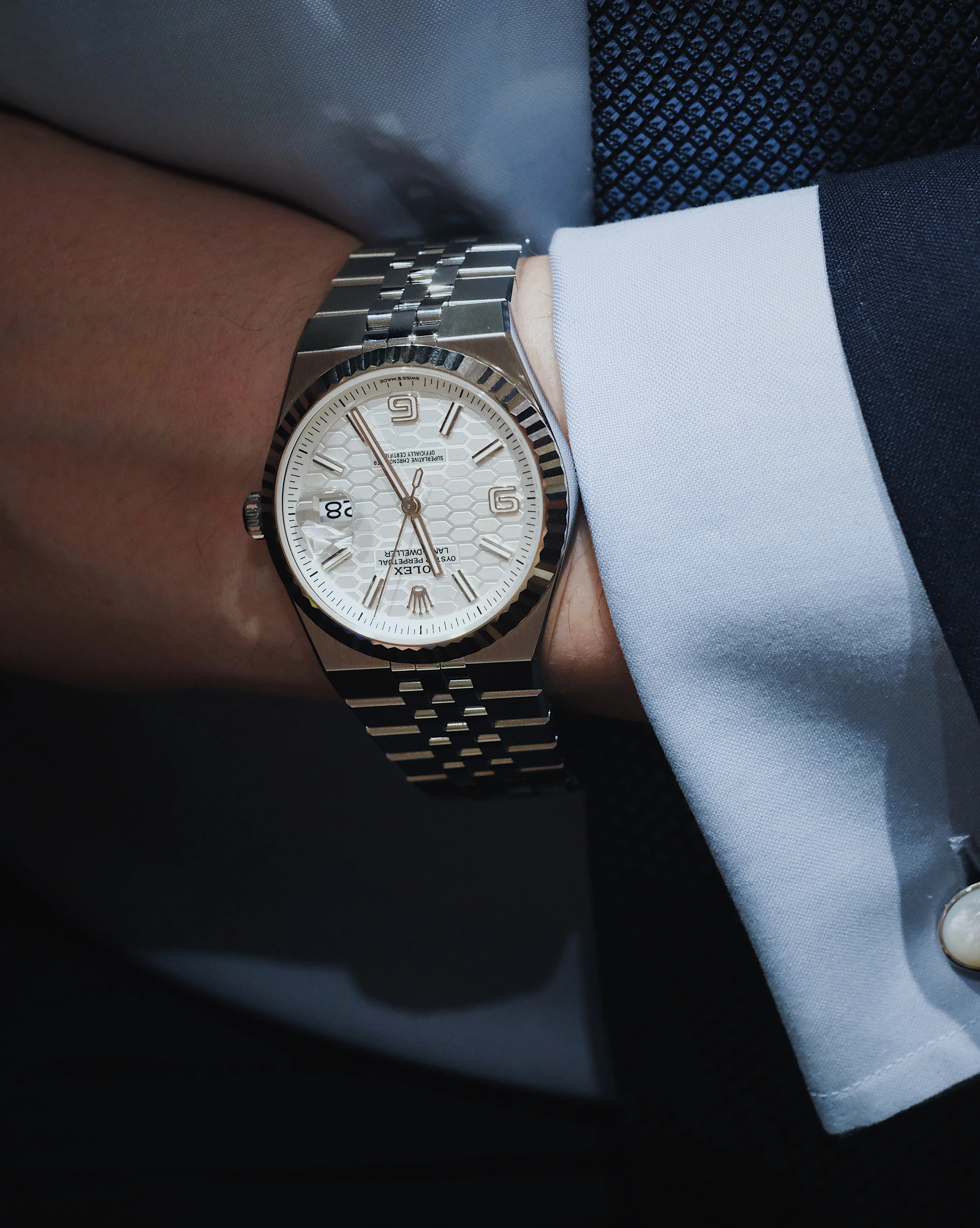 Rolex Land Dweller being worn on a man’s wrist wearing a blue shirt and navy suit