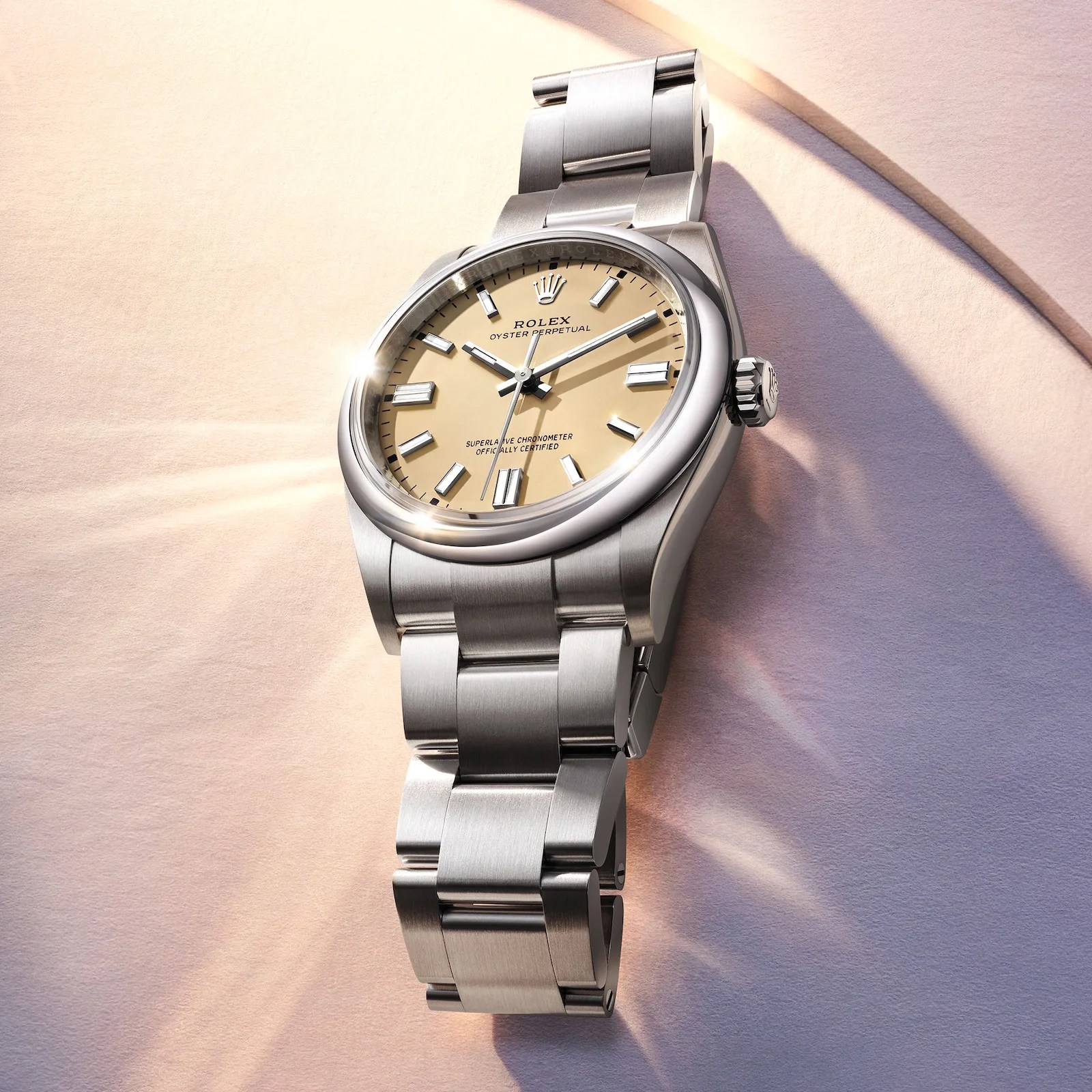 The 2025 Rolex Oyster Perpetual with a new Beige-colored dial lying against a sandy-looking backdrop with lens flares.