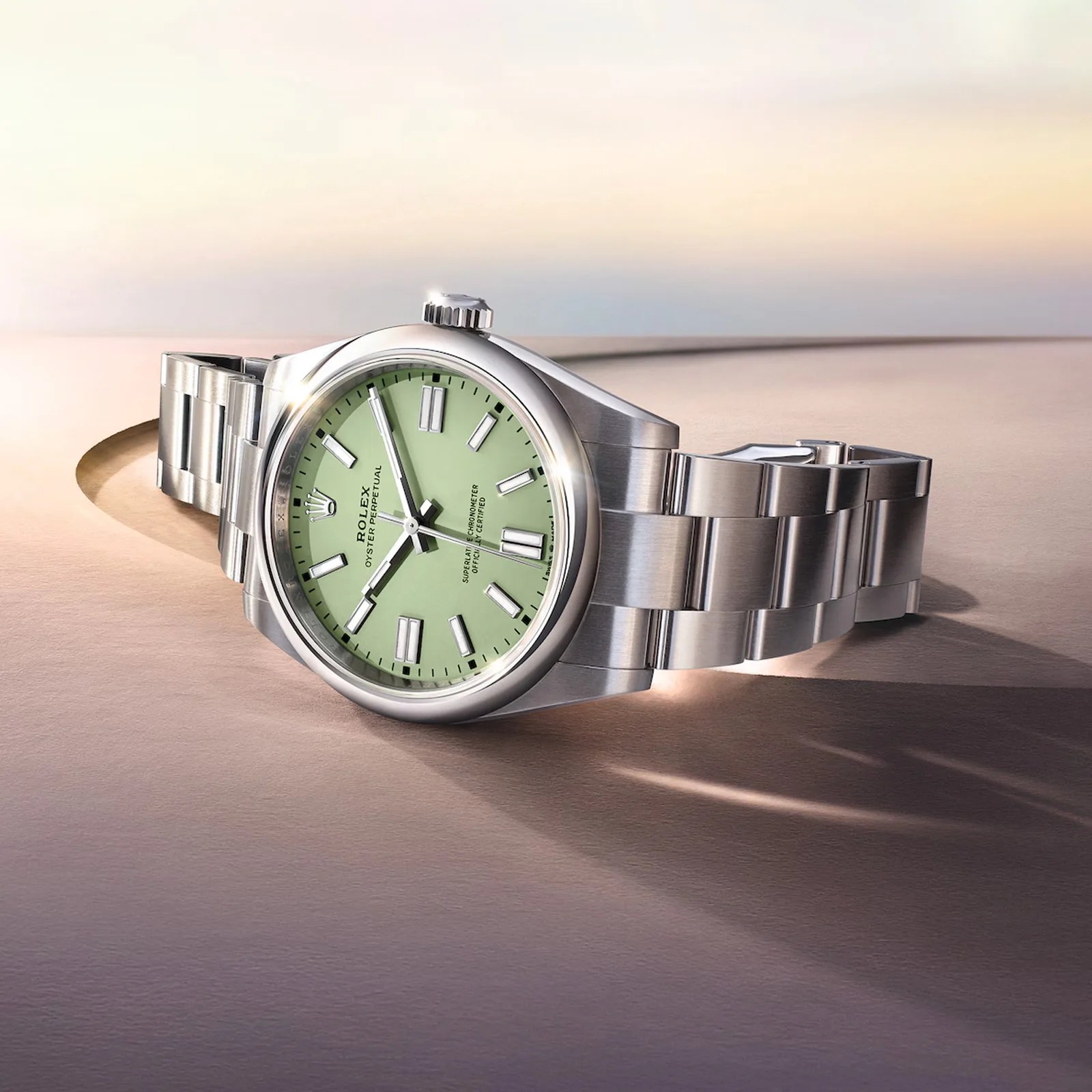 A view of the 2025 Rolex Oyster Perpetual with a new pistachio-colored dial shown laying against a rendered, sand-like background.