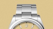A close-up of the top portion of the dial of the Rolex Oyster Perpetual 36 released in 2025 against a light beige background.