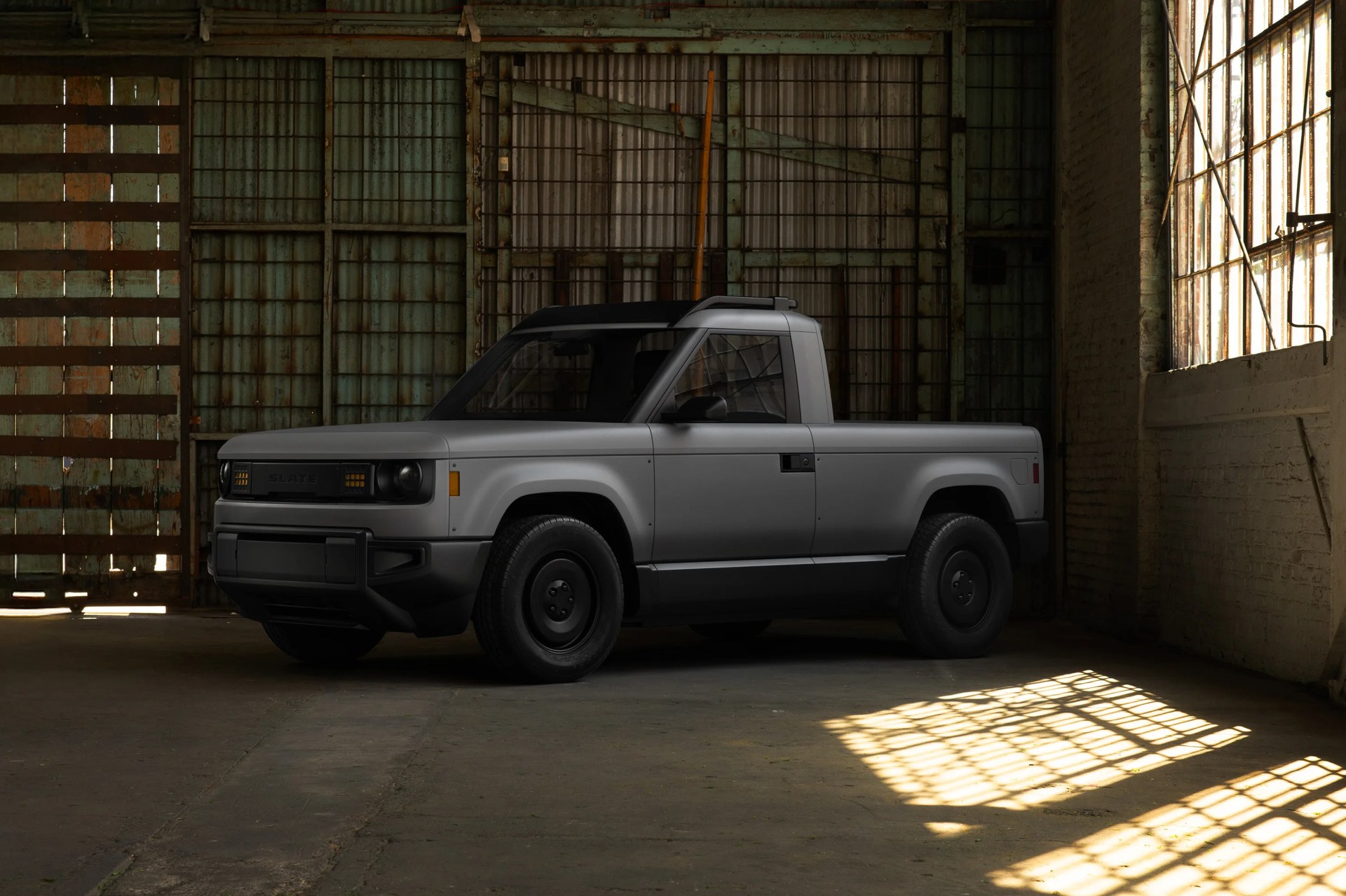 The Slate Auto Blank Slate EV Truck in a warehouse with sun streaming in. 