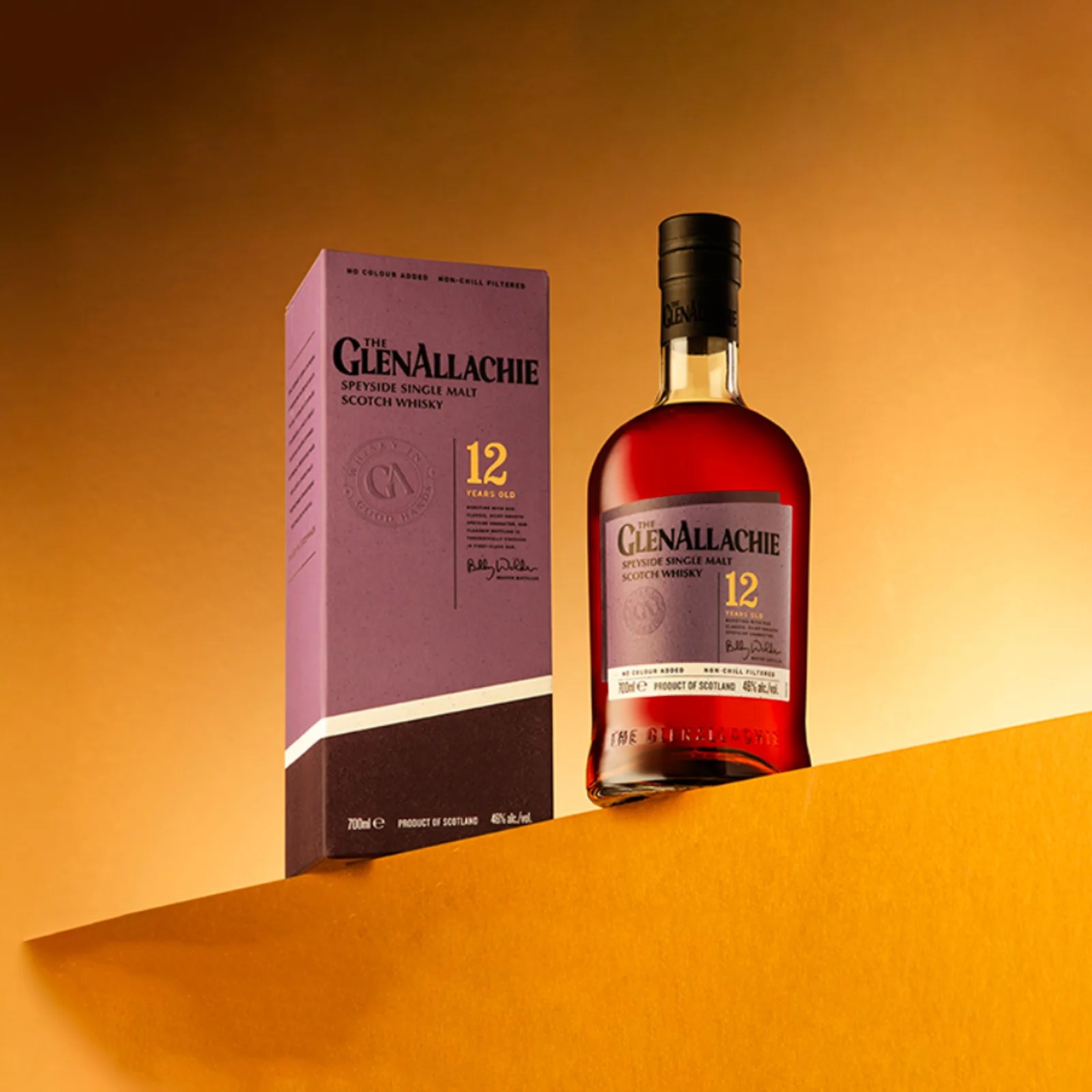 A bottle of The GlenAllachie 12-Year-Old sitting on a yellow ledge and standing next to its packaging box.