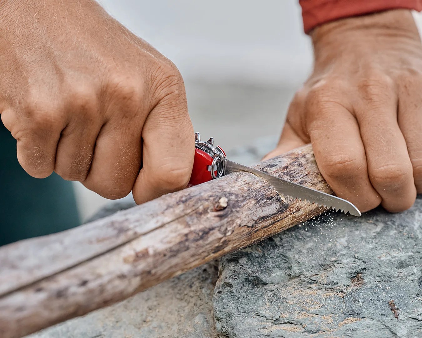 man cutting piece of wood using Victorinox Huntsman Multi-Tool