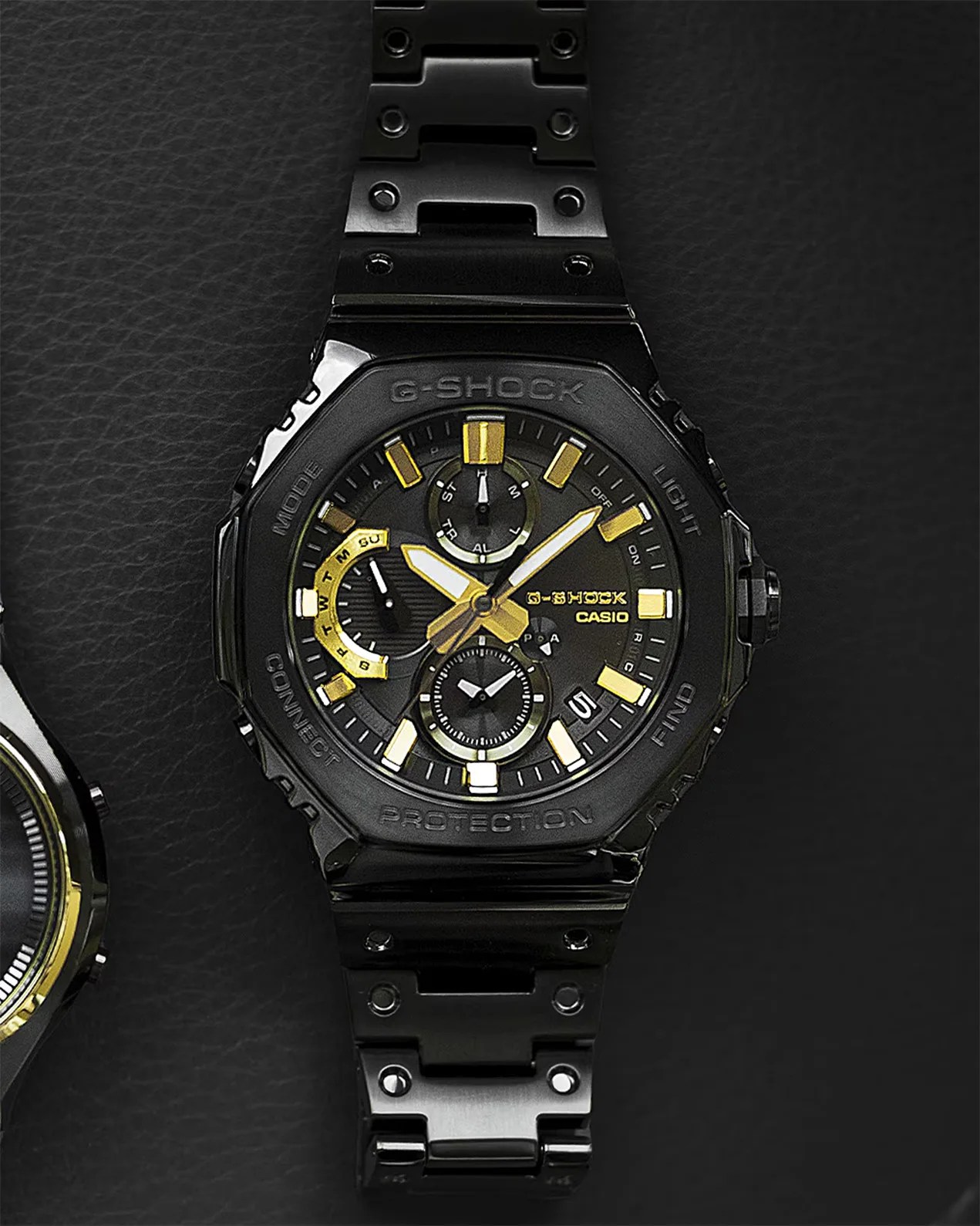 a black g-shock watch with gold dial details